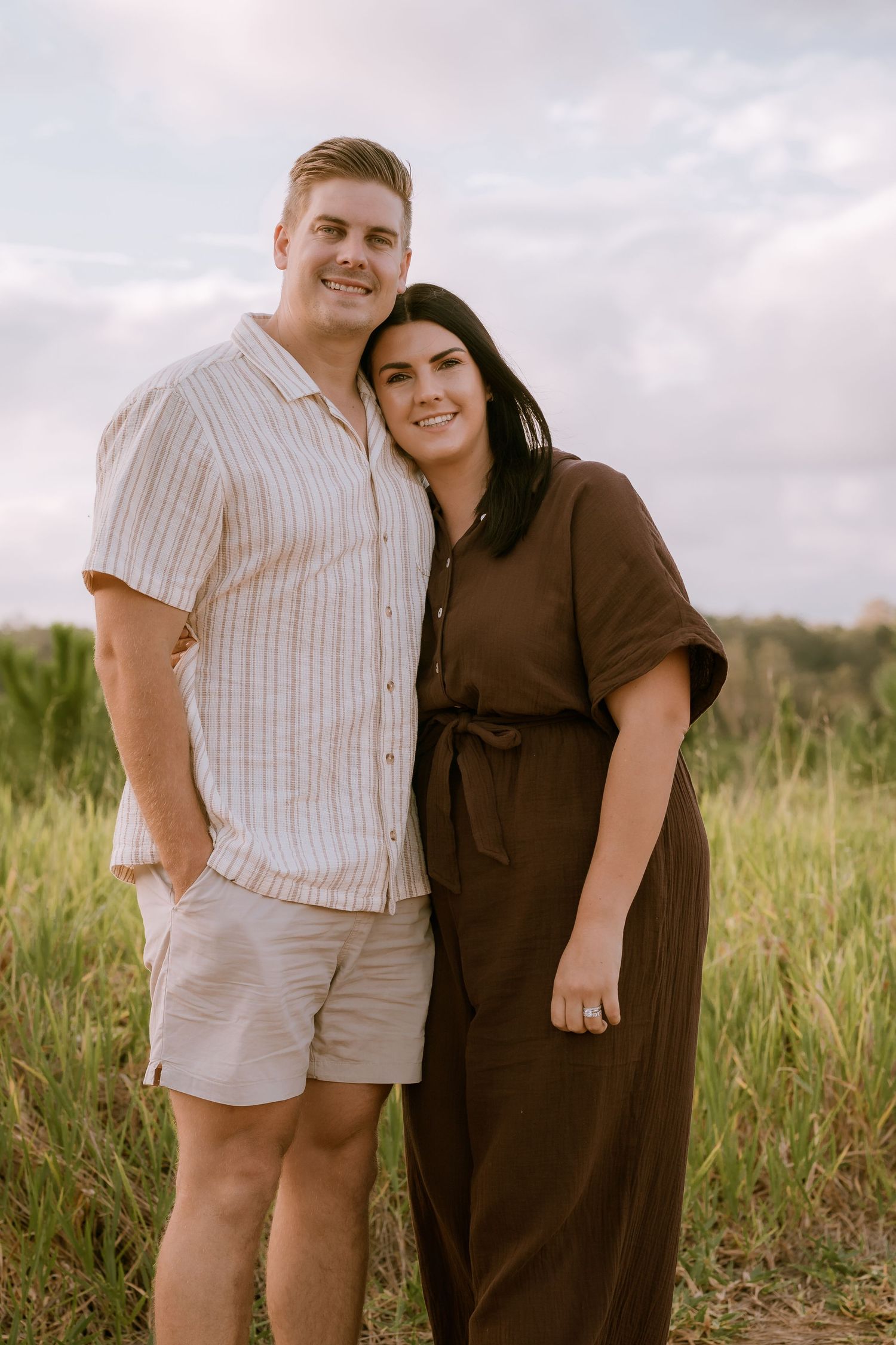 Brisbane couples and engagement photographer — couple standing together in golden hour field, relaxed and candid outdoor session by Joy Fill