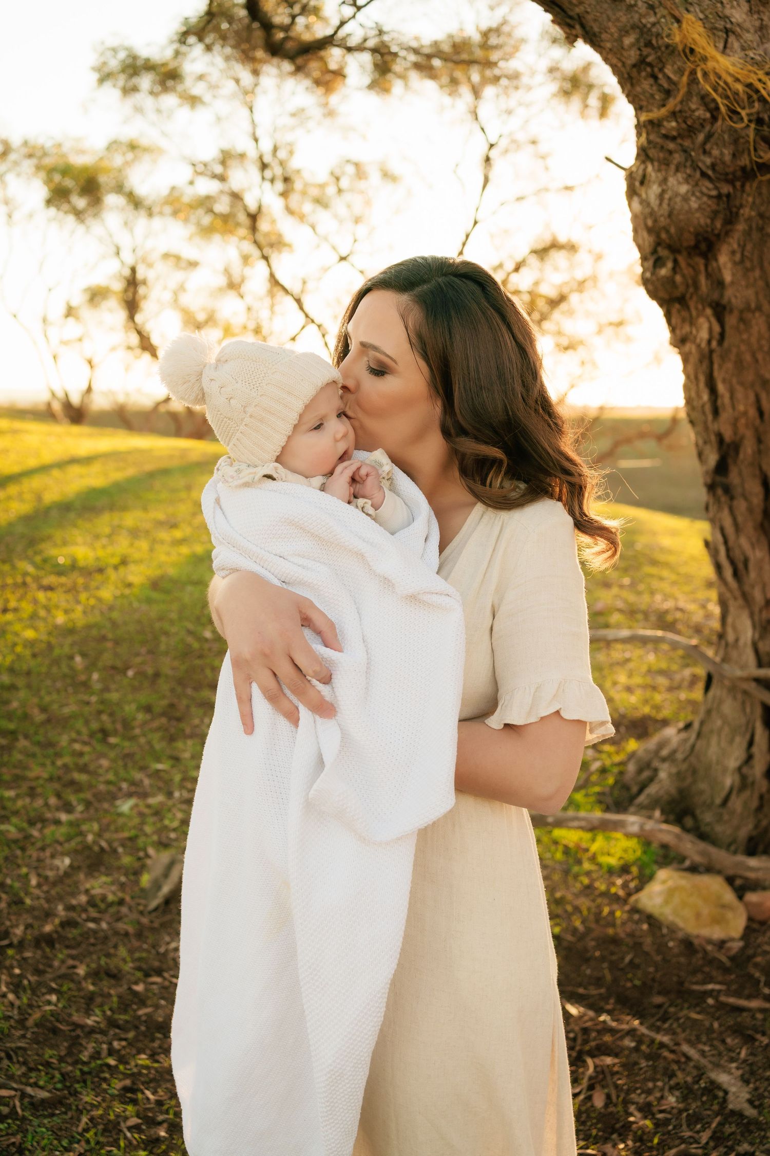 Brisbane maternity photographer — expectant mother in white dress holding her baby bump during golden hour outdoor maternity session by Joy