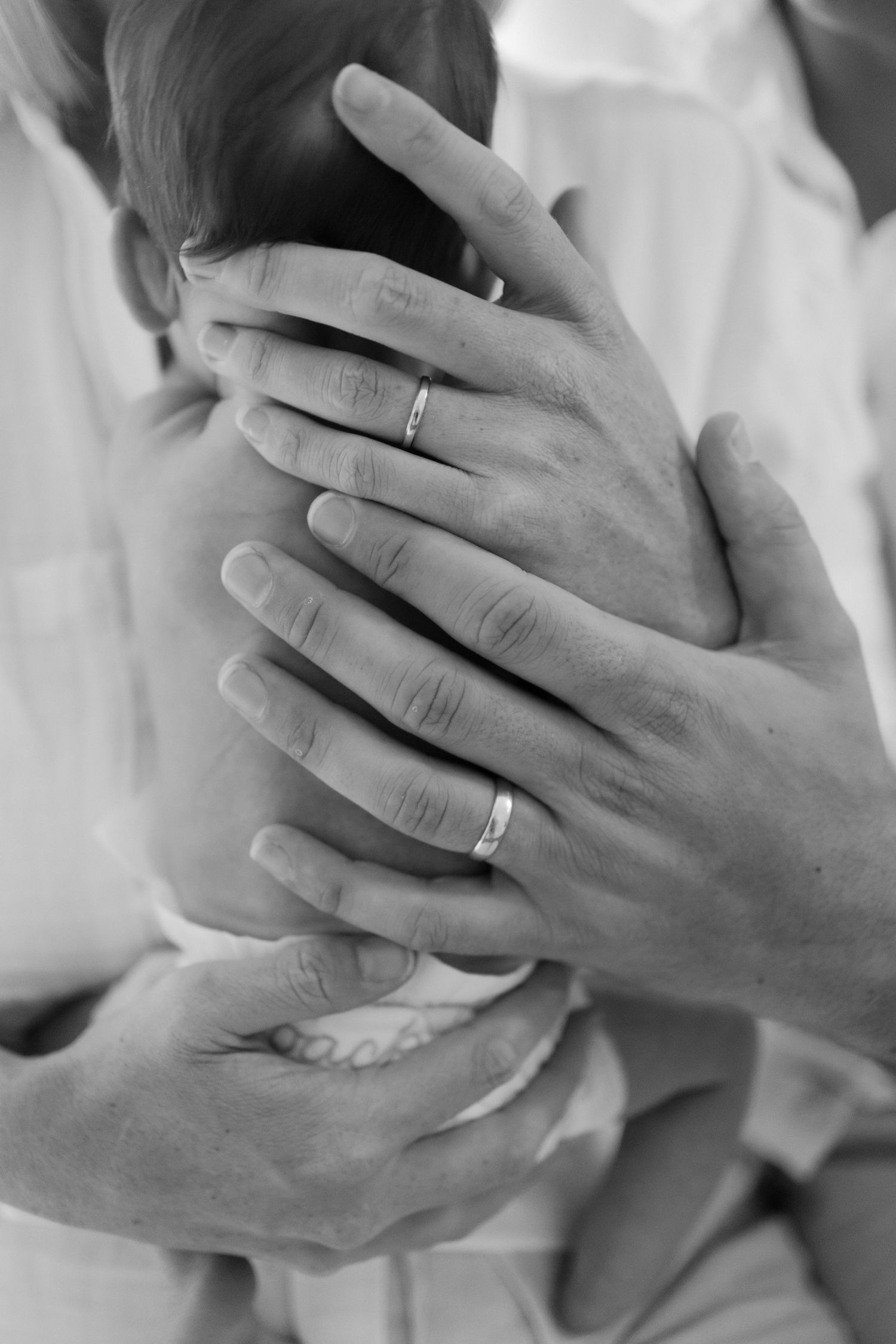 Brisbane newborn photographer — black and white close-up of parents' hands cradling their tiny newborn, precious detail shot from in-home se