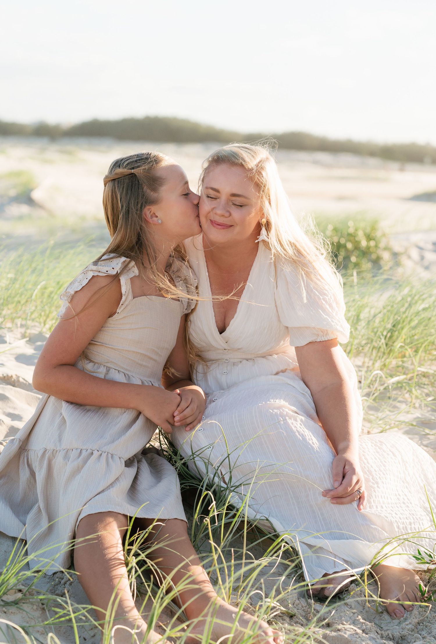 Brisbane family photographer — two women sharing a joyful moment sitting together on beach sand dunes in natural light, Joy Filled Photograp