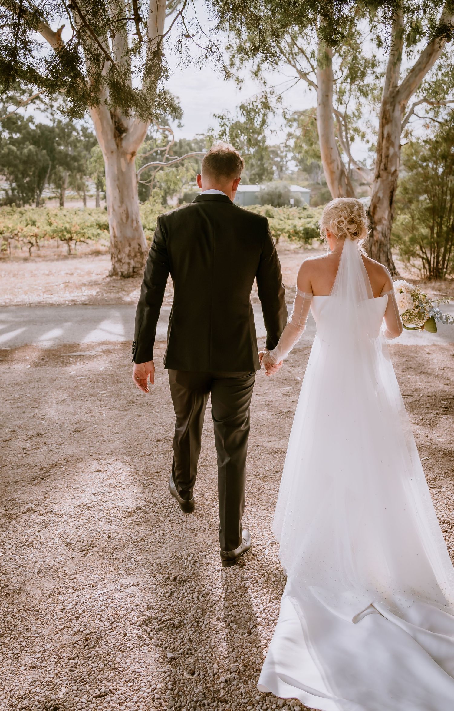 Brisbane wedding photographer — bride walking alone through an outdoor setting, beautiful editorial back portrait with flowing veil by Joy F
