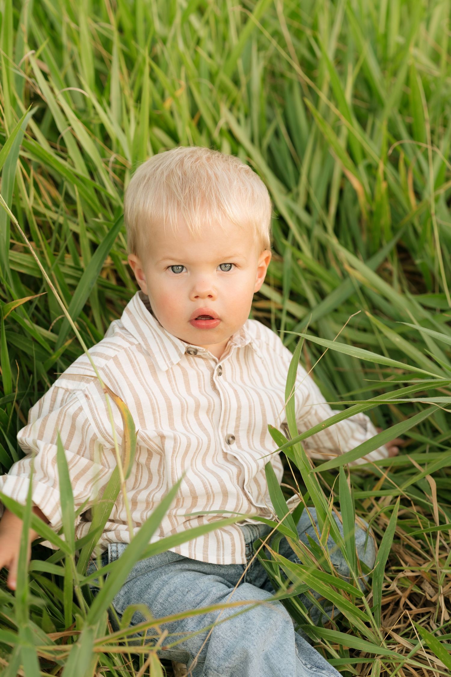 Brisbane family photographer — adorable toddler sitting in lush green grass smiling, candid lifestyle session by Joy Filled Photography Nara
