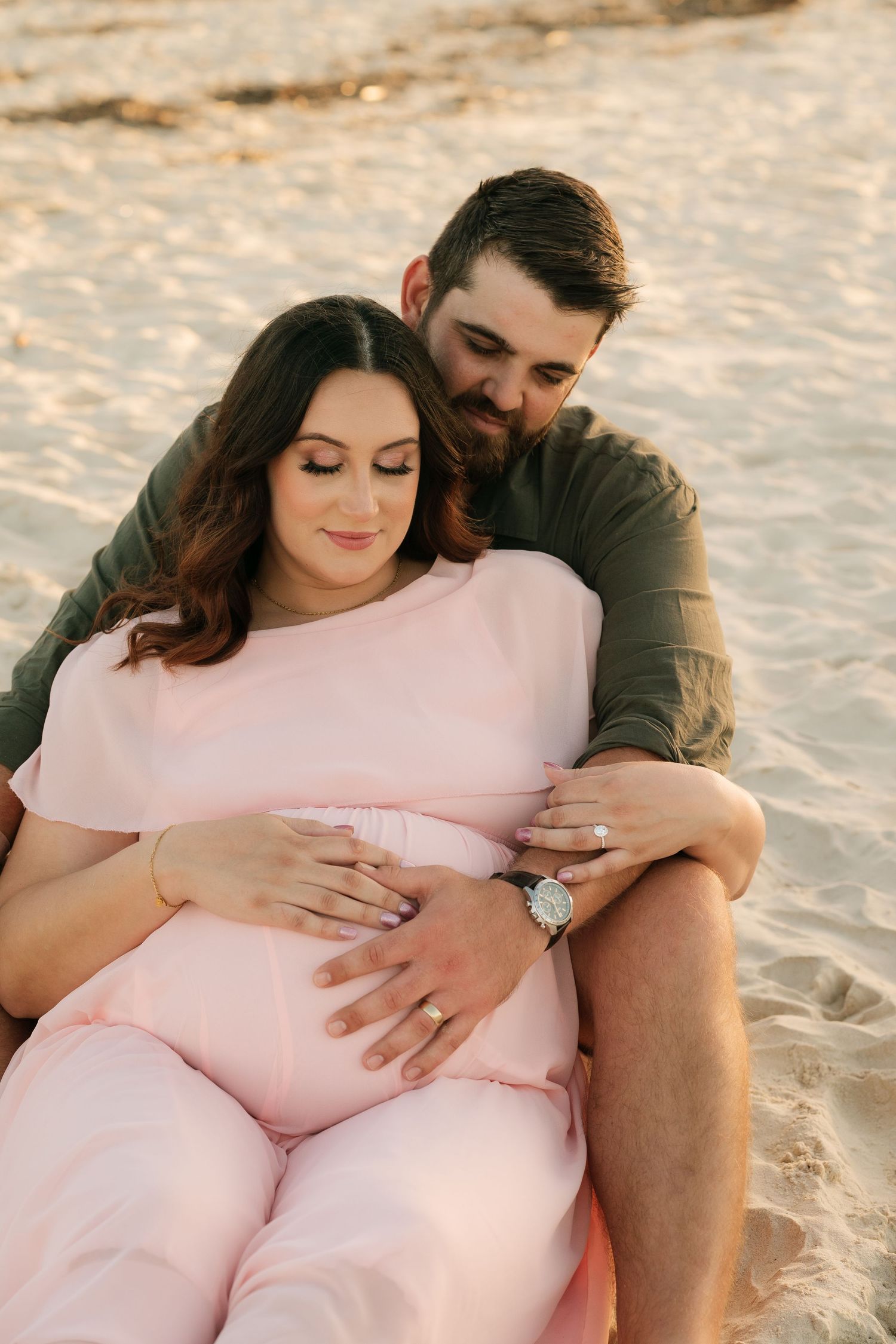 Brisbane maternity photographer — couple embracing outdoors at golden hour, expectant mother cradling baby bump, emotive maternity session b