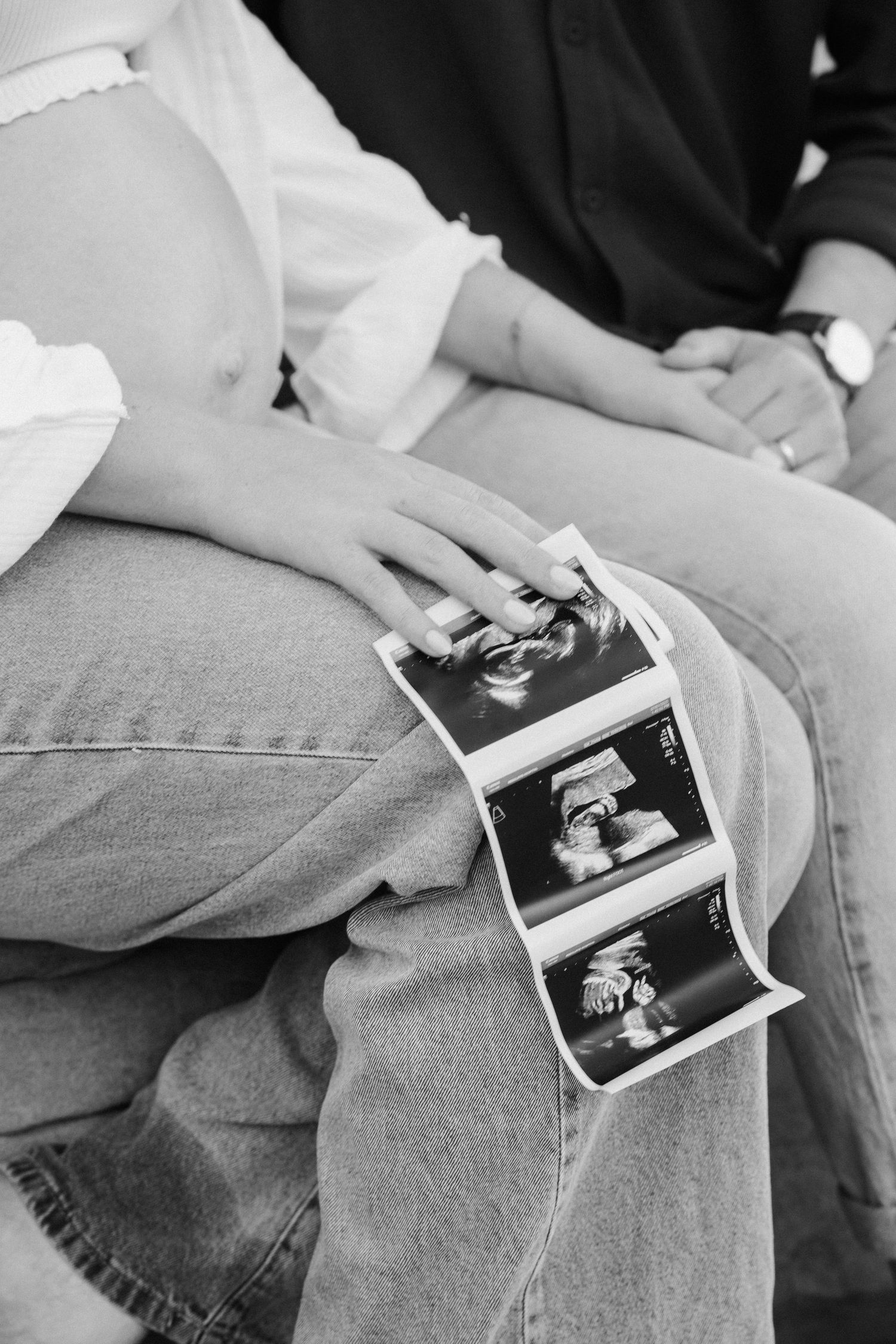 Brisbane maternity photographer — black and white close-up of couple holding ultrasound scan together, emotional pregnancy announcement capt