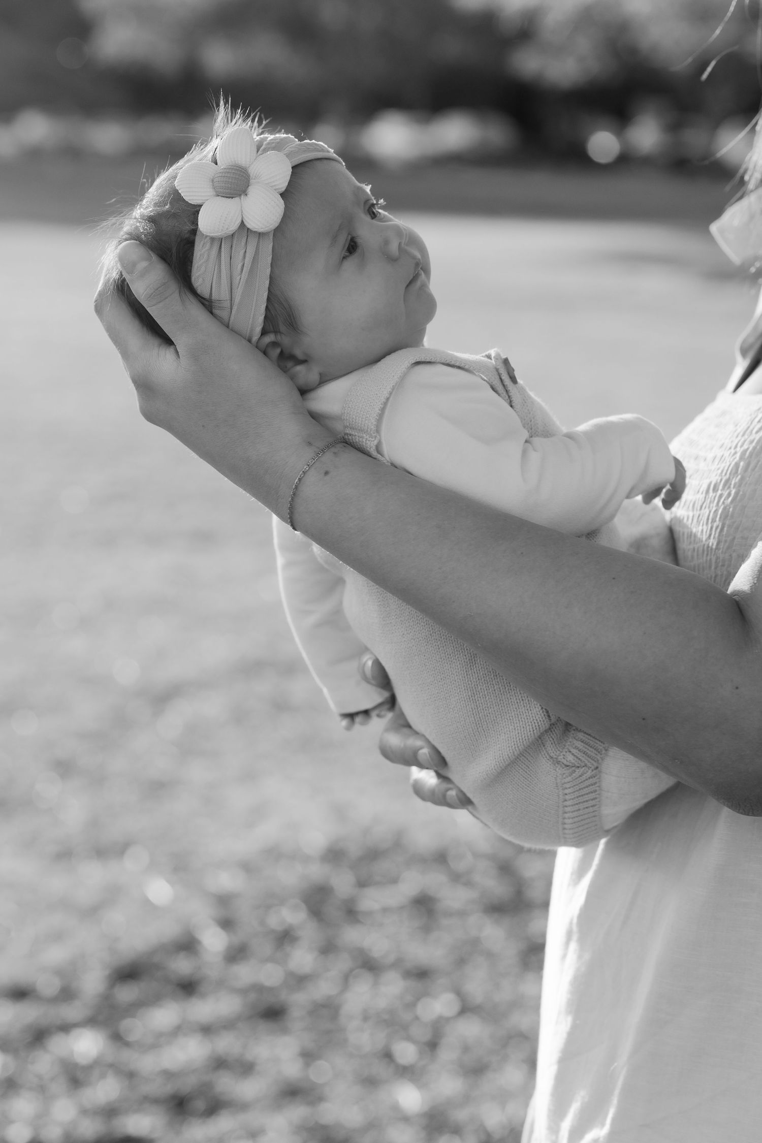 Brisbane family photographer — black and white close-up of parent's hands gently holding sleeping newborn baby, tender detail shot by Joy Fi