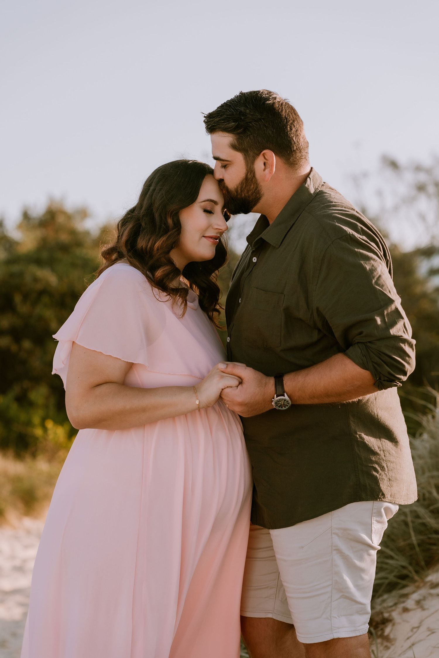 Brisbane maternity photographer — close-up of mother lifting baby outdoors in warm afternoon light, joyful and authentic family moment by Jo