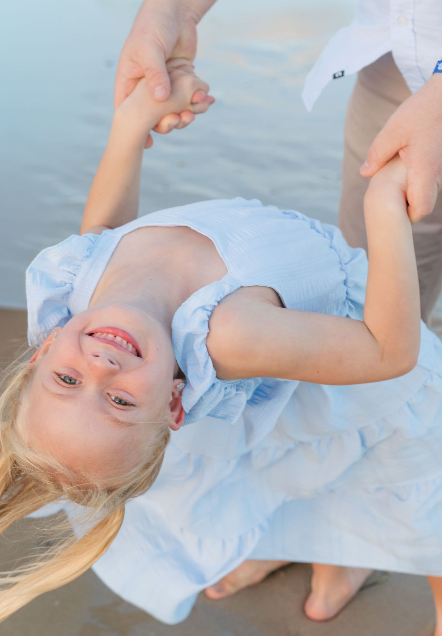 Brisbane family photography — playful moment of young child tilting and laughing near the water during a beach family session by Joy Filled