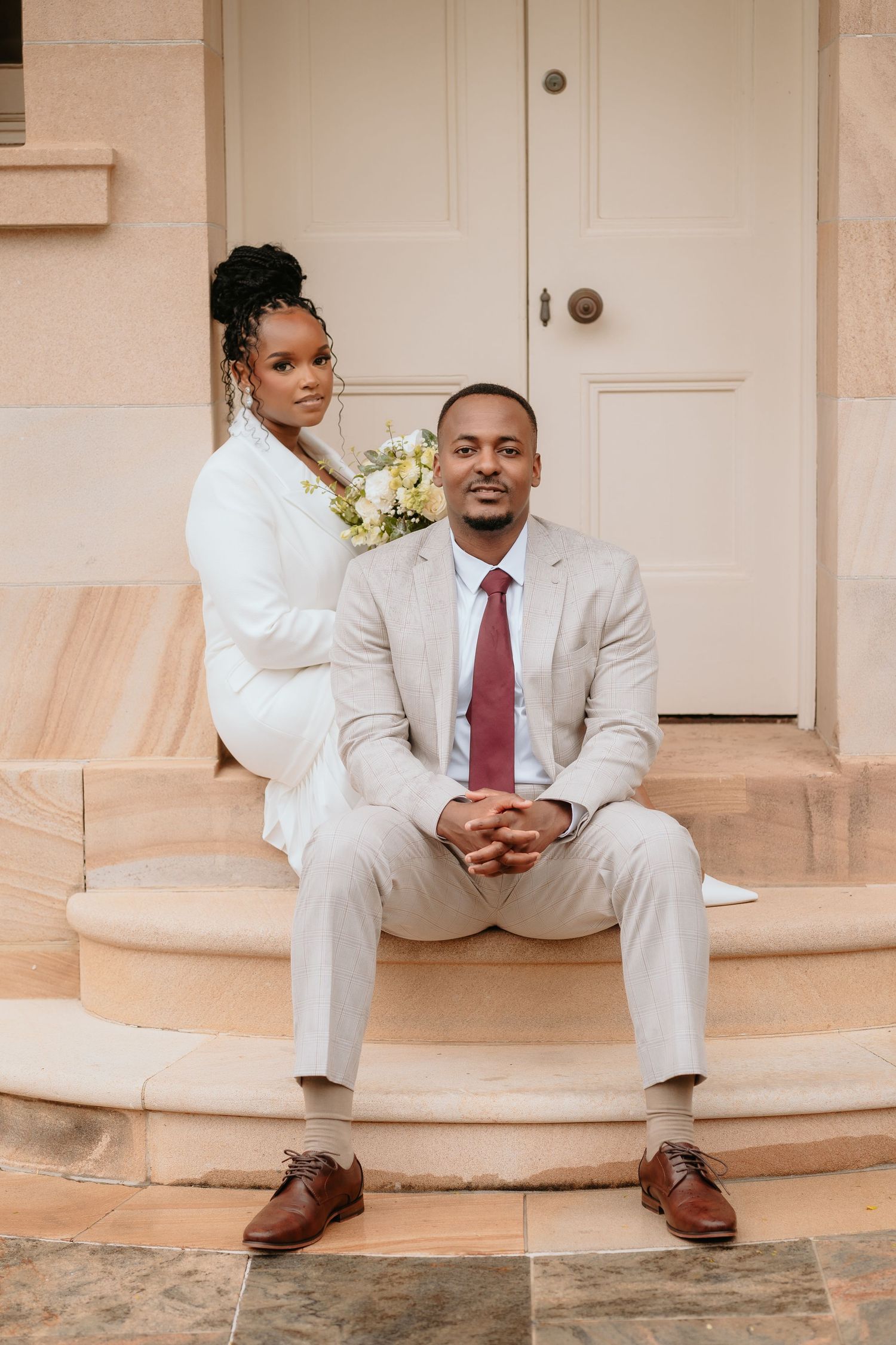 Brisbane wedding photographer — couple in matching white outfits sitting together on steps, relaxed and joyful elopement portrait by Joy Fil
