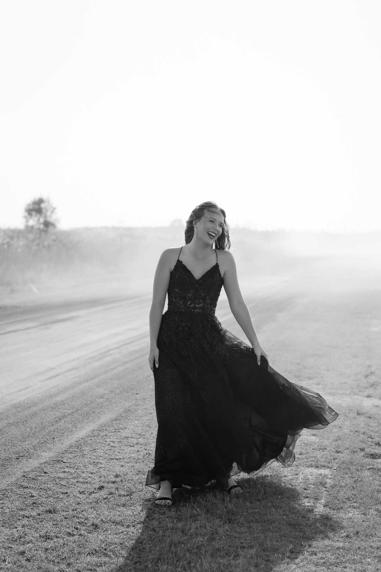 Brisbane wedding photographer — black and white portrait of bride in flowing black dress walking confidently on beach, dramatic and emotive