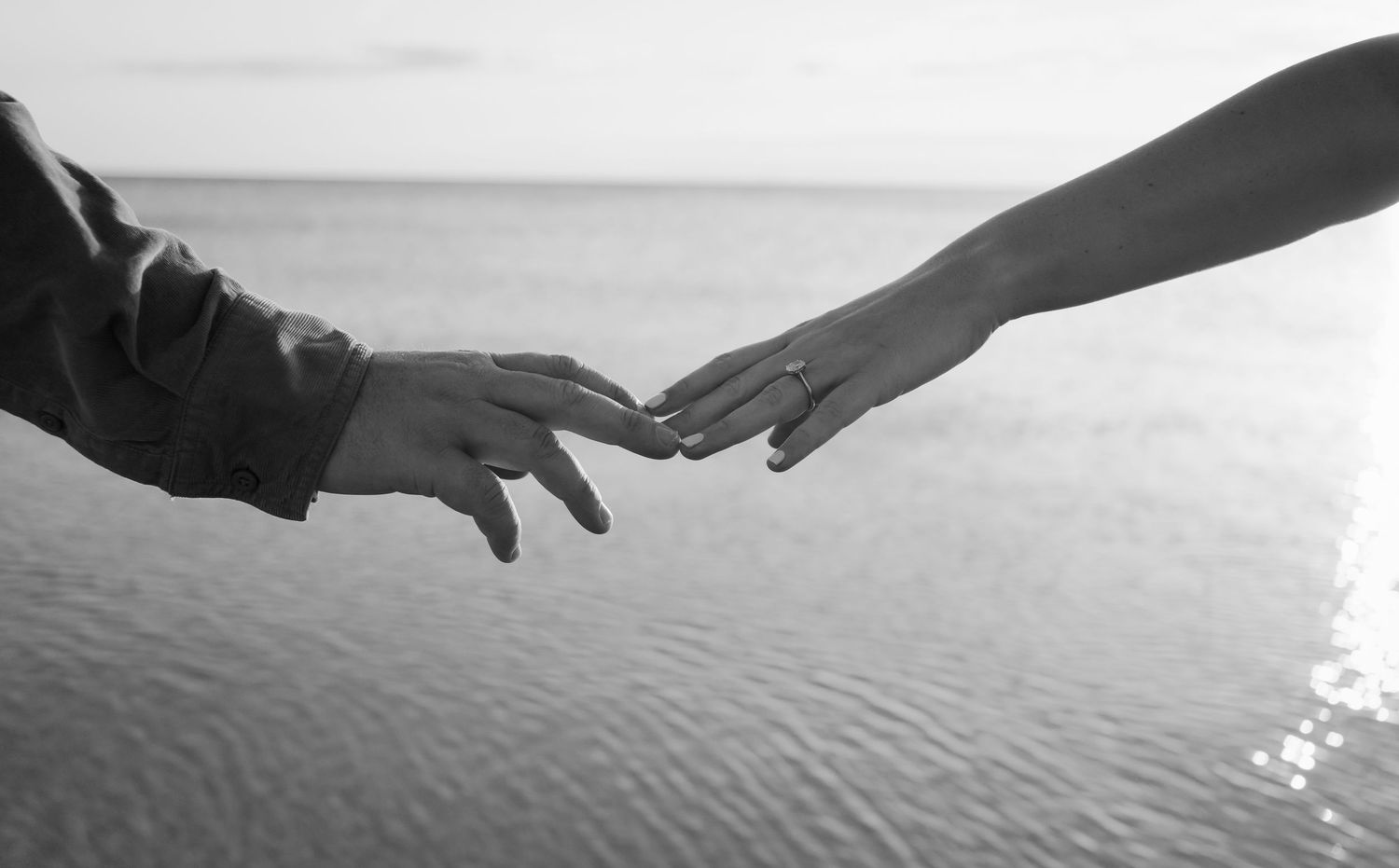 Brisbane wedding photographer — black and white close-up of bride and groom holding hands by the water, romantic and tender wedding moment b