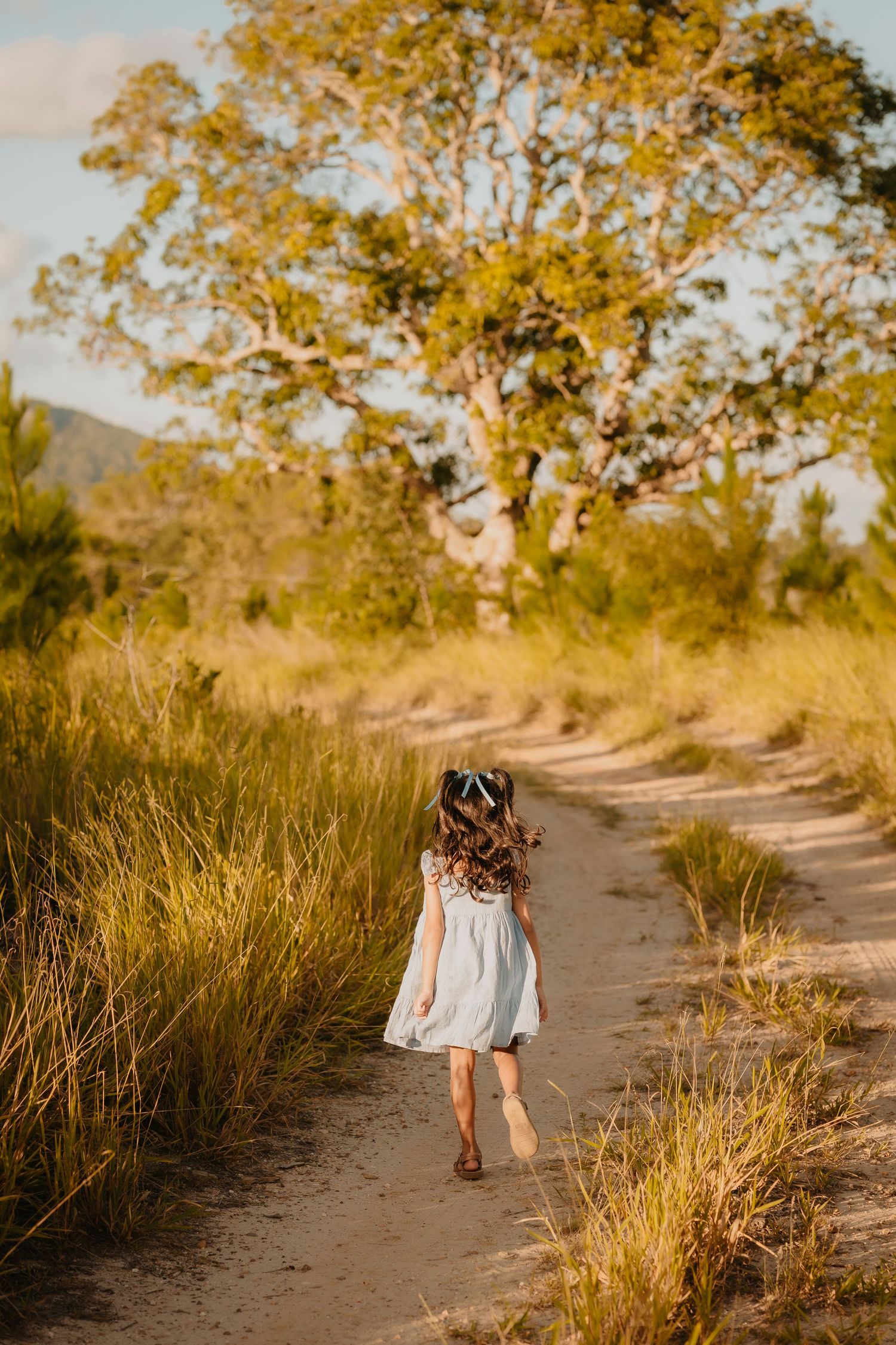 Brisbane family photographer — young girl walking alone along a golden field path in warm afternoon light, Joy Filled Photography Brisbane N