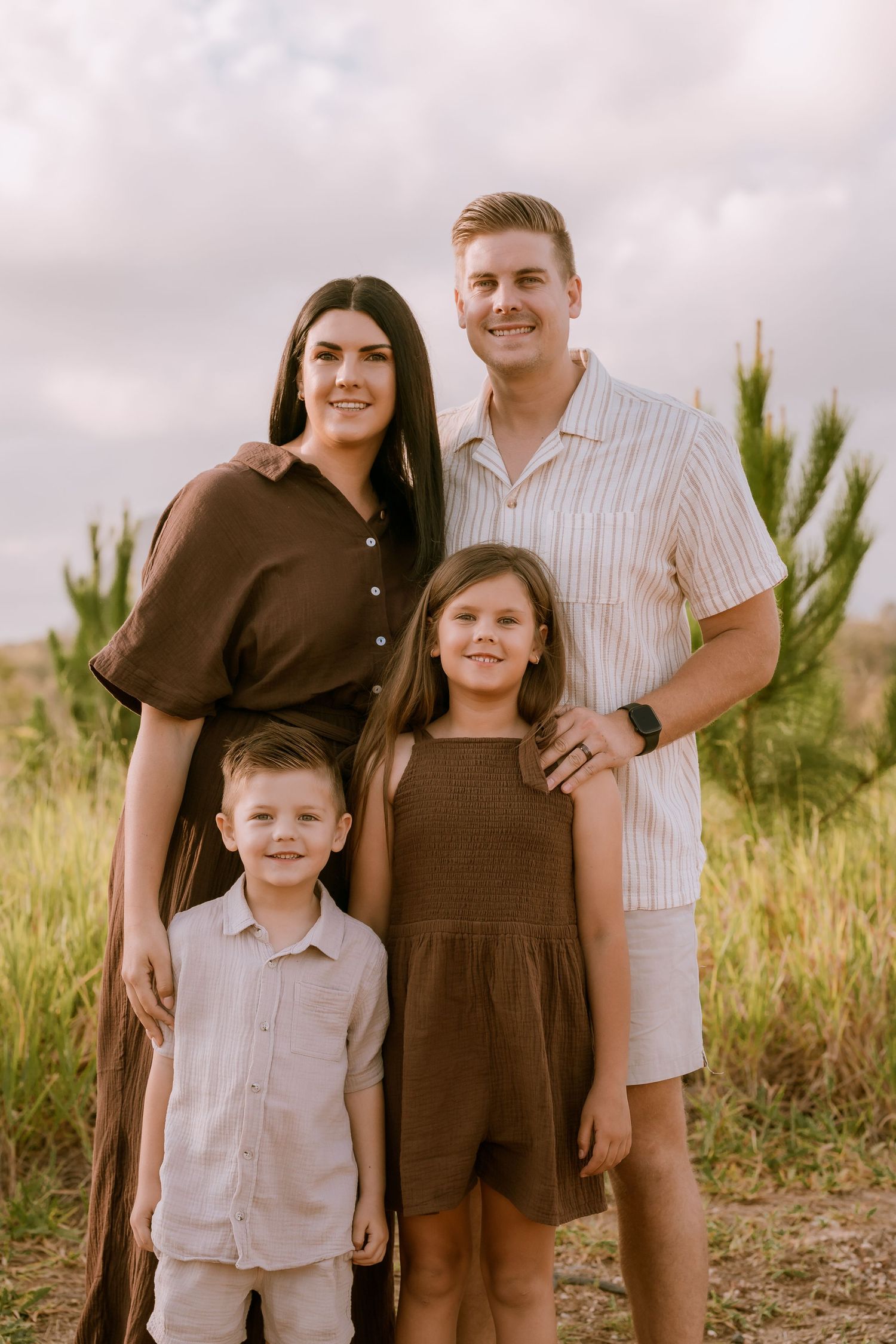 Brisbane maternity photographer — couple embracing in a sunflower field with mountain backdrop, warm and joyful outdoor maternity session by