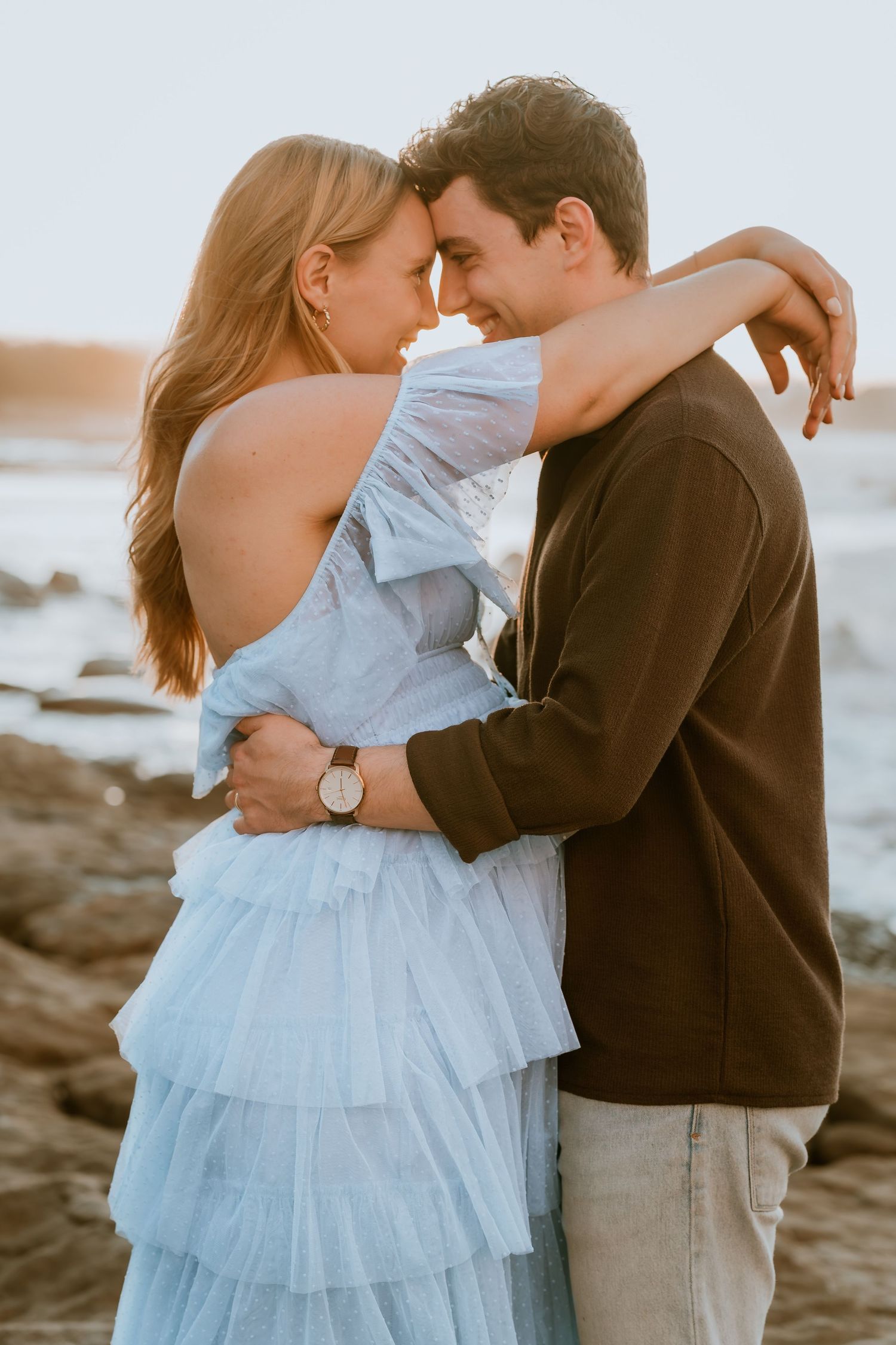 Brisbane maternity photographer — couple sharing a forehead kiss outdoors, expectant mother in blue dress with partner in warm tones, emotiv