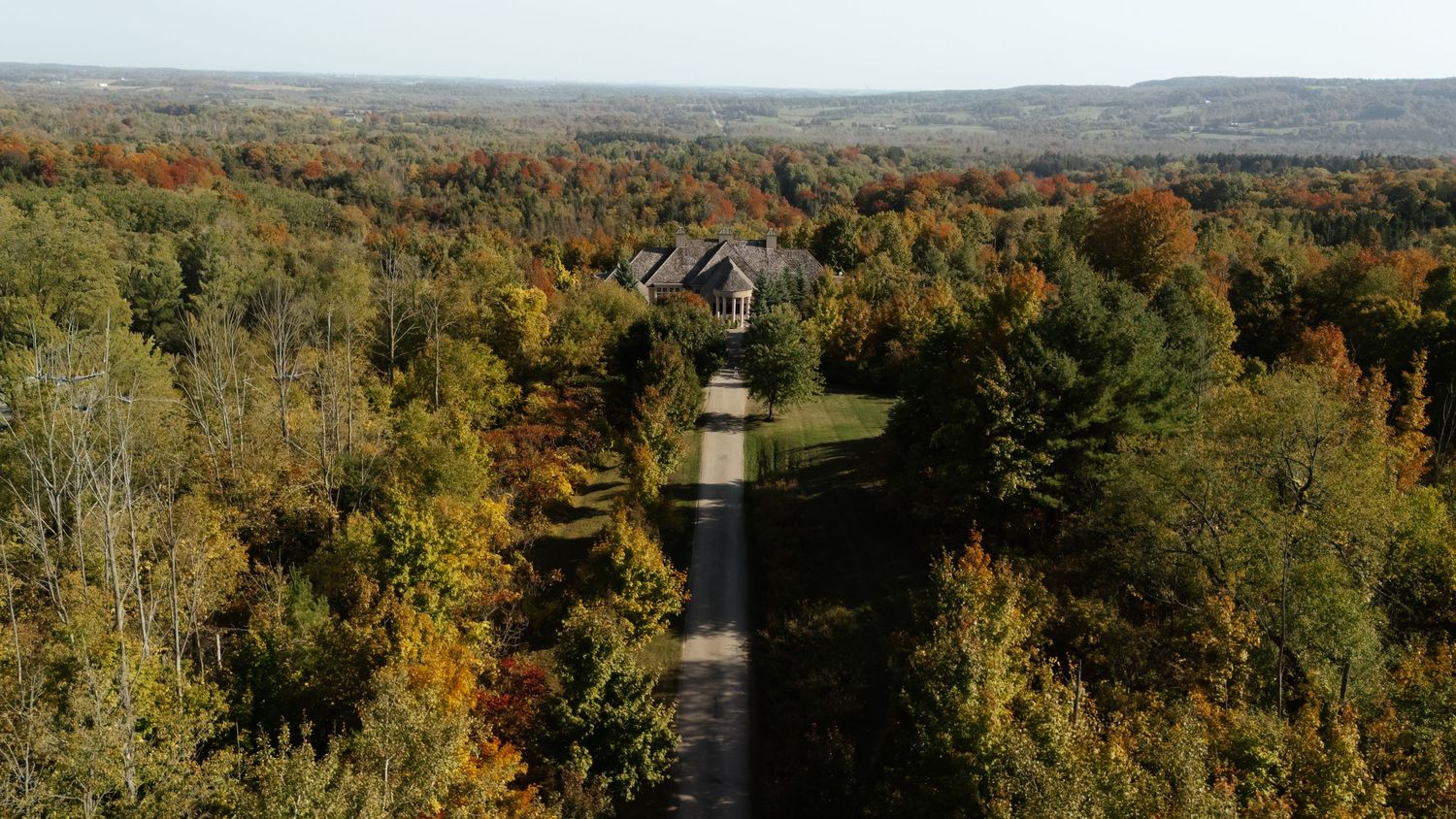 Panoramic autumn landscape view of rolling hills covered in colorful fall foliage stretching to the horizon.