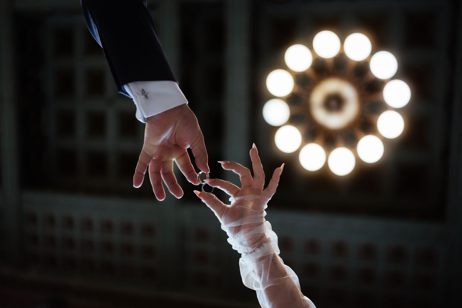 A sequence of hands reaching upward against a dark background with circular lights creating a dramatic silhouette effect.