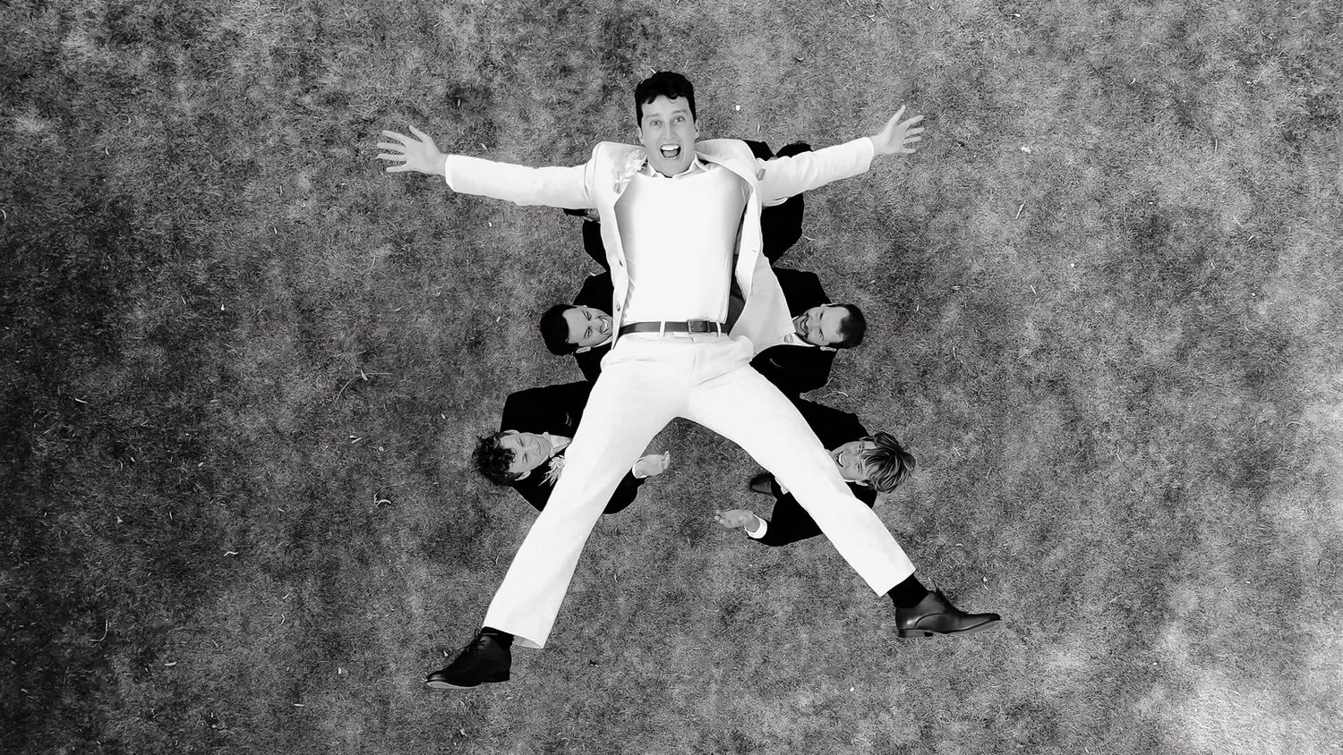 A creative overhead shot of groomsmen forming a star pattern on the ground in black and white in Cambridge.