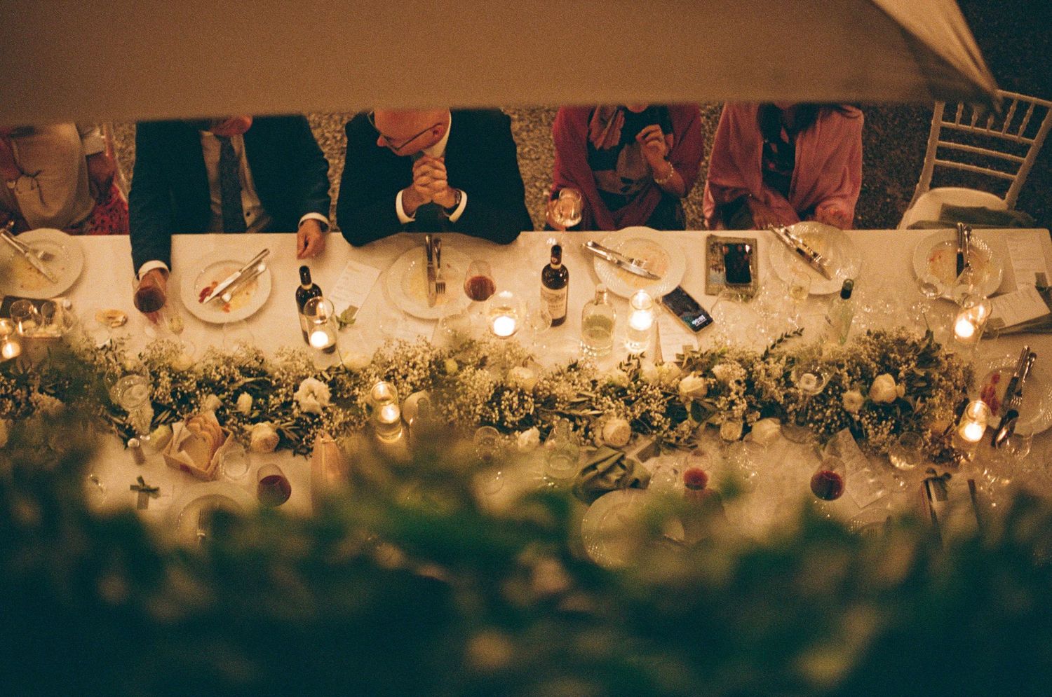 Overhead view of beautifully decorated wedding reception table with floral centerpieces and candles.