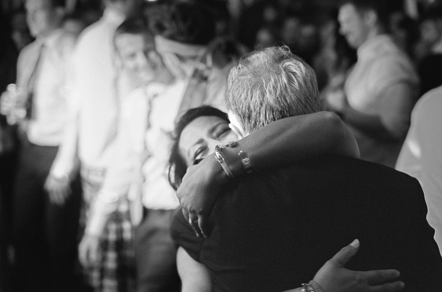 Emotional black and white photo of bride sharing a heartfelt hug on the wedding dance floor.