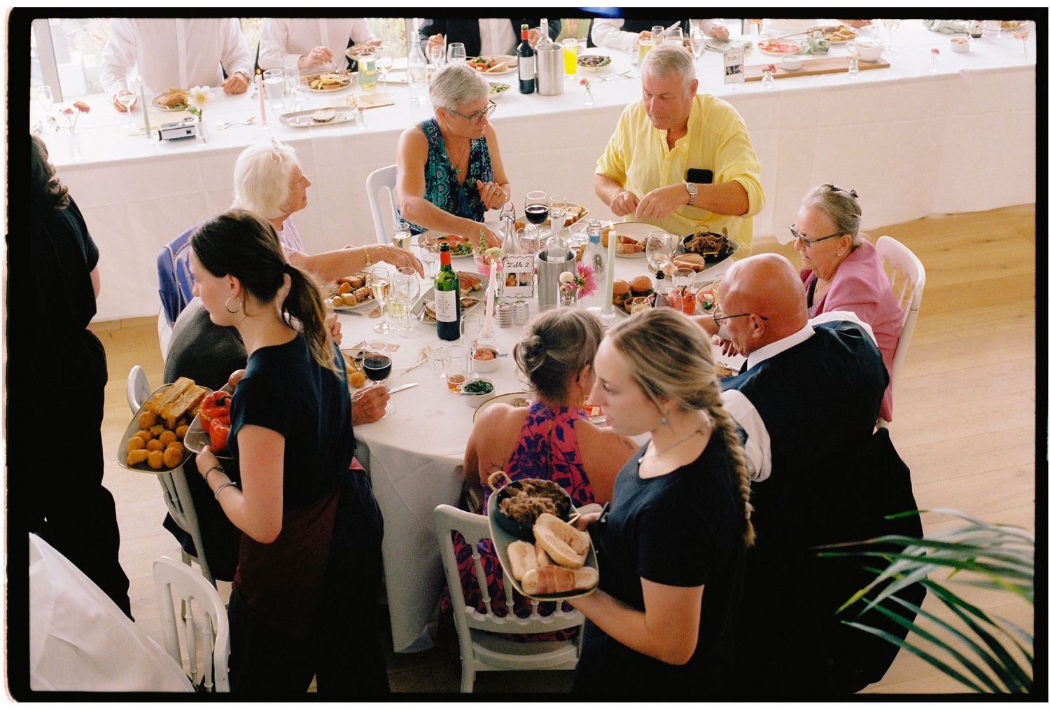 Guests gathered around a large dining table sharing a meal at an elegant indoor celebration or family gathering.