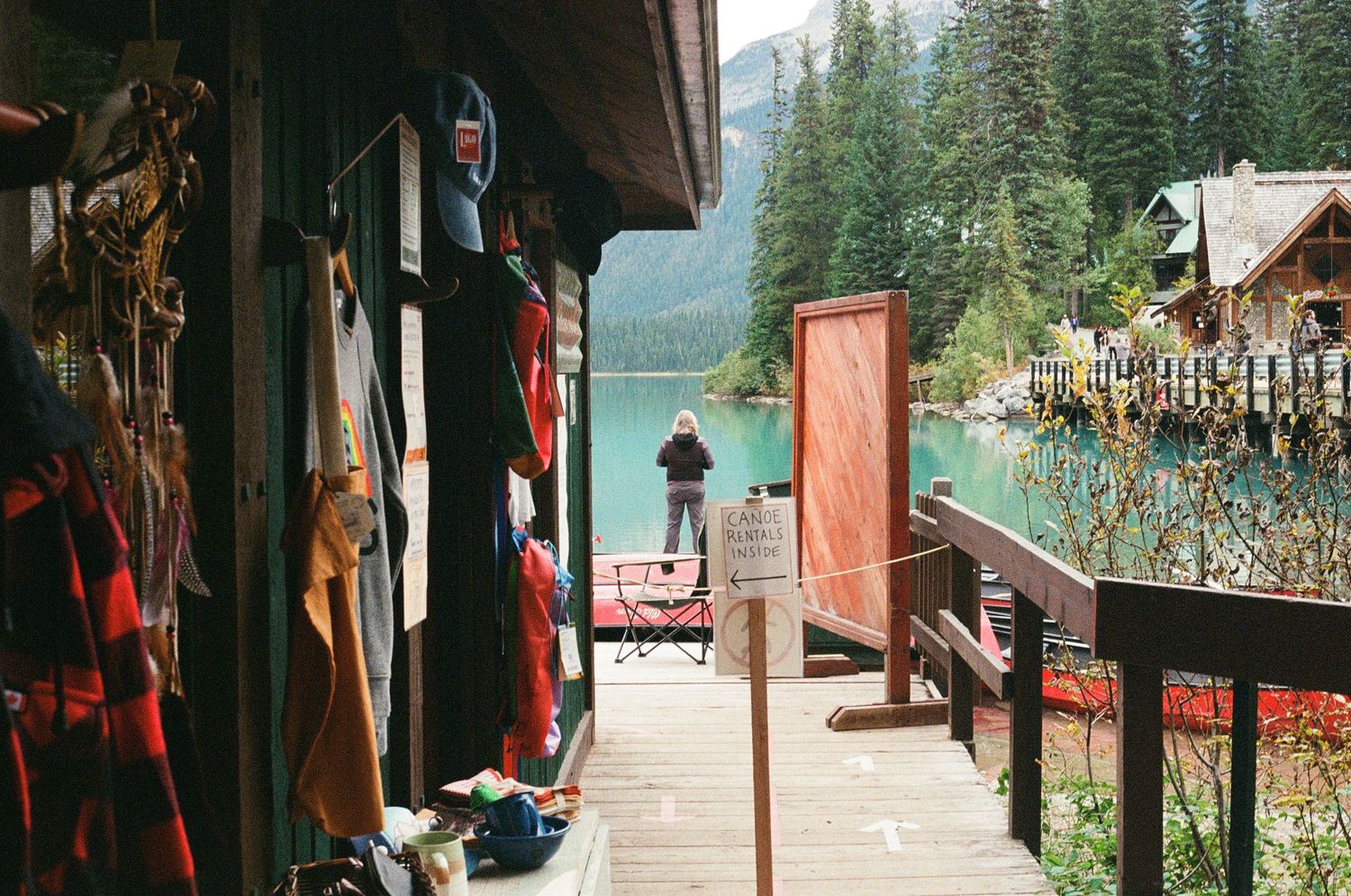 Rustic mountain lake shop deck with outdoor gear overlooking turquoise glacial waters.