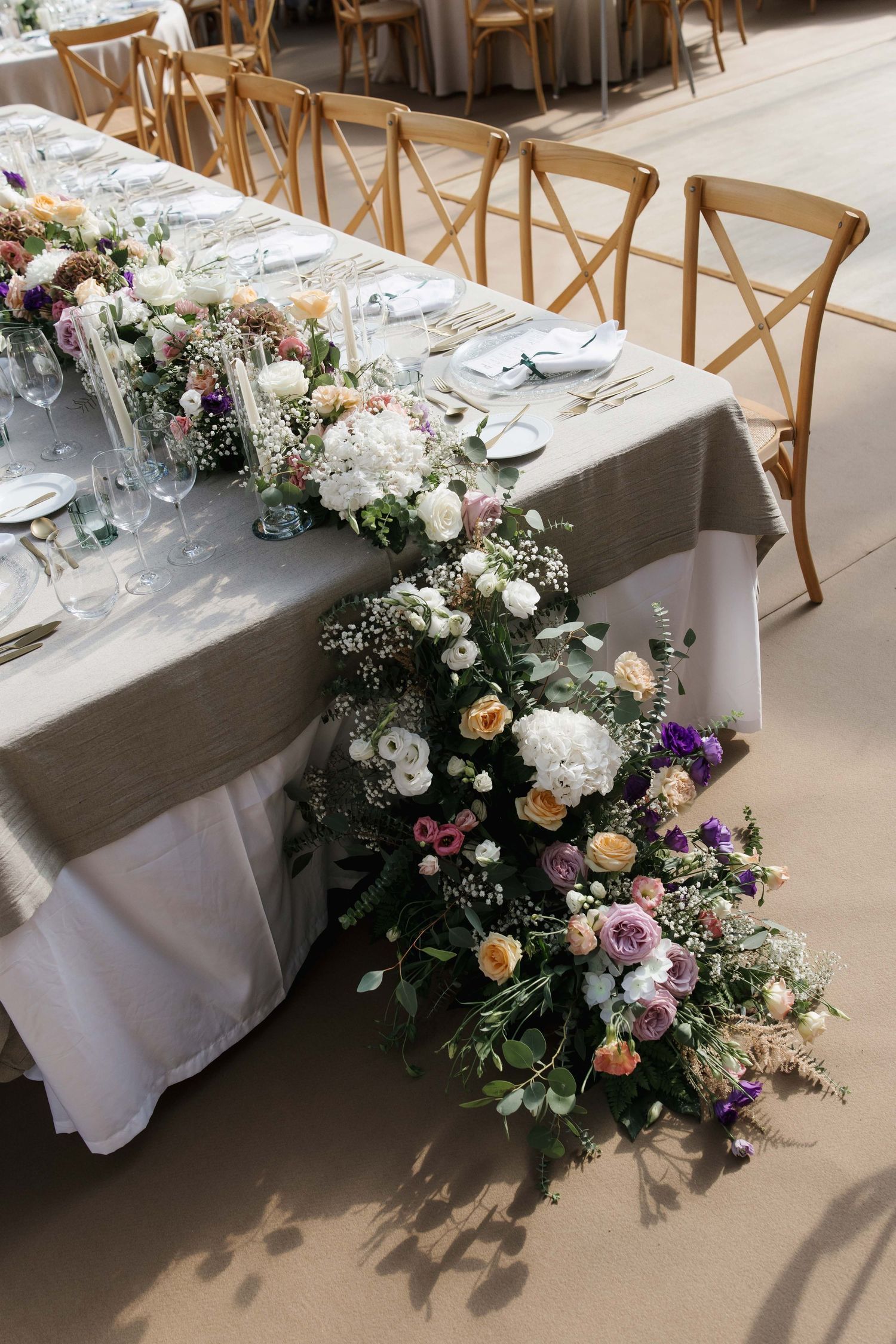 Luxurious wedding reception table adorned with cascading purple, white, and peach floral centerpiece.