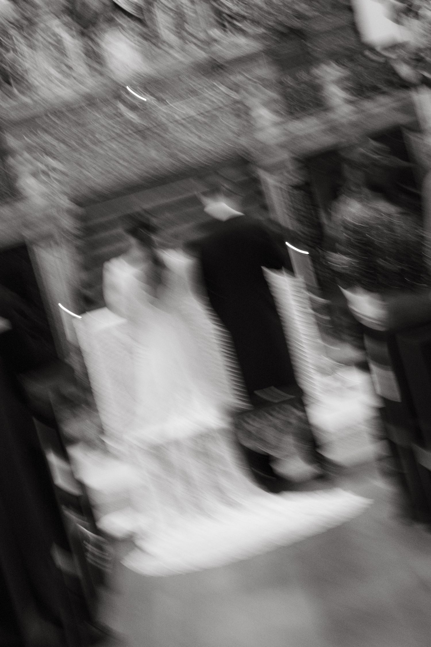 Artistic blurred black and white wedding photo capturing motion of bride and groom walking together.