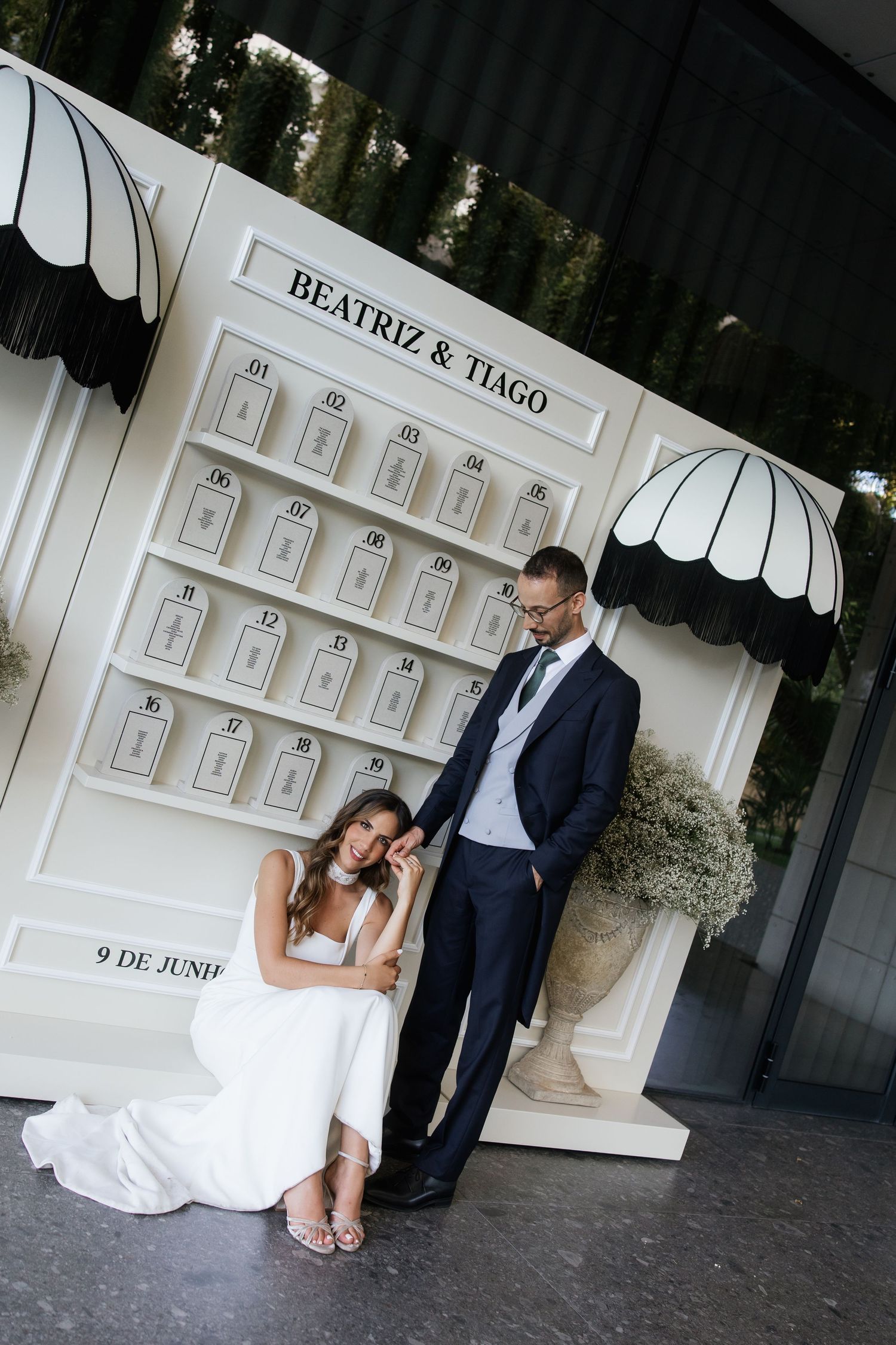 Bride and groom pose beside elegant white seating chart display reading Beatriz and Tiago, 9 de Junho.