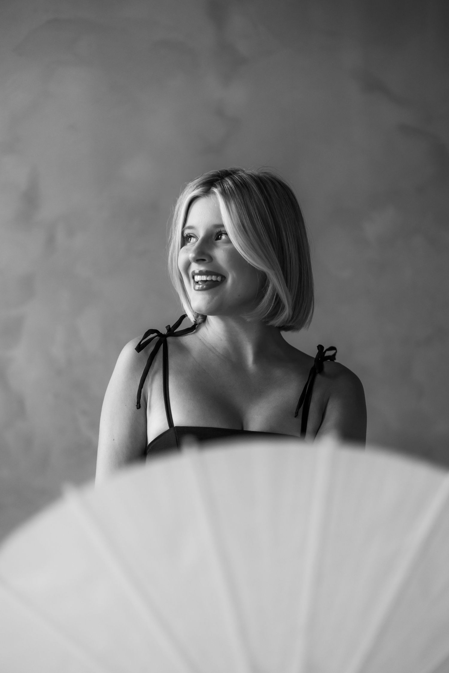 Black and white artistic portrait series showing a person in white dress against textured background.