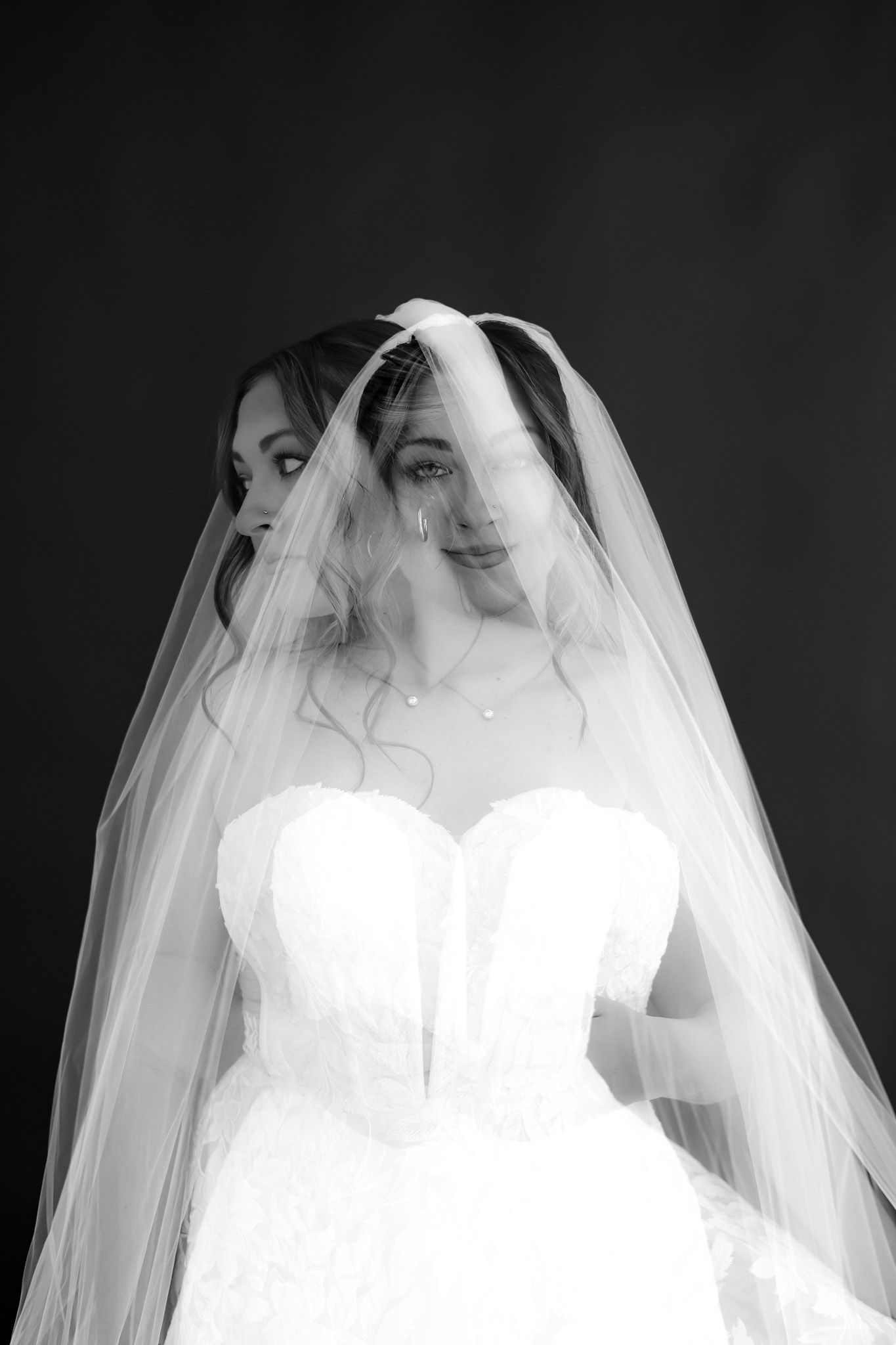 Artistic black and white bridal portrait series showing flowing white wedding dress and veil details.