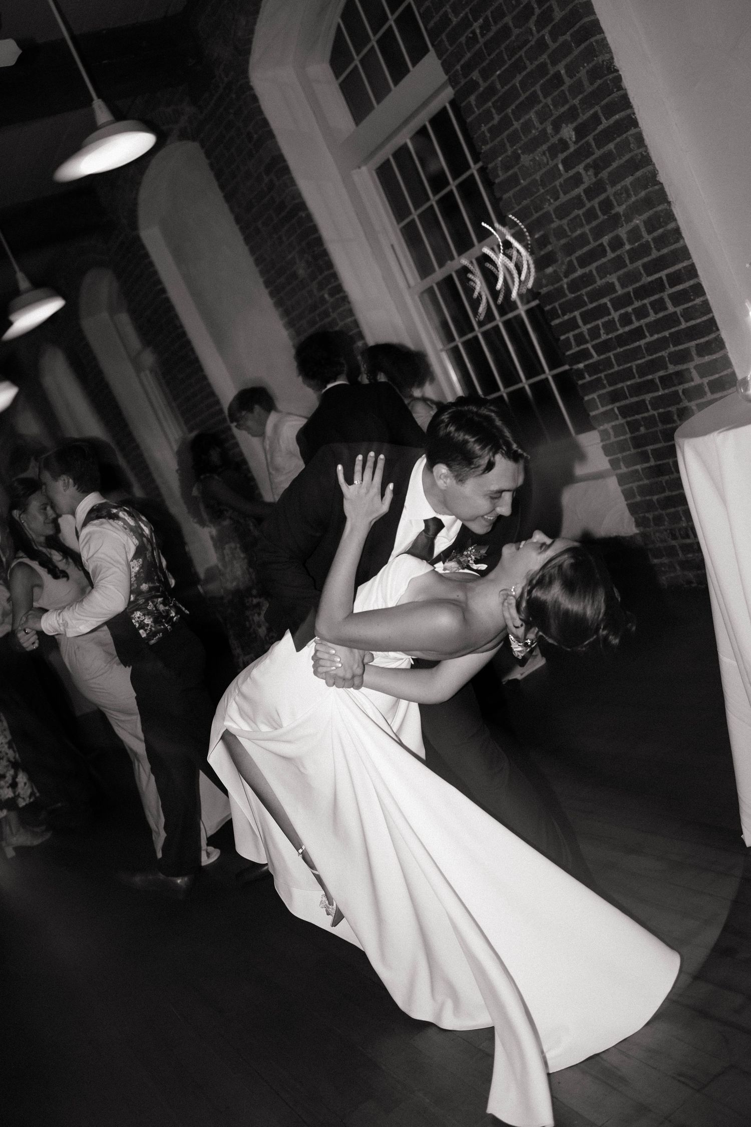 Black and white photo of bride and groom sharing a romantic dip dance at their wedding reception.
