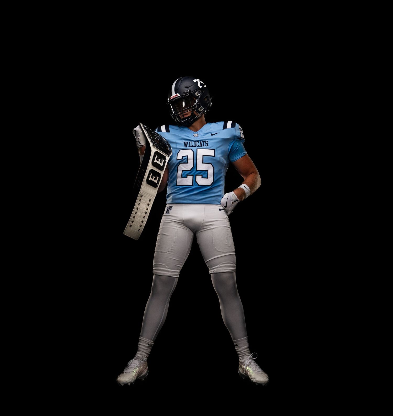 Football player #25 in light blue Titans uniform holding a blocking pad against black background.