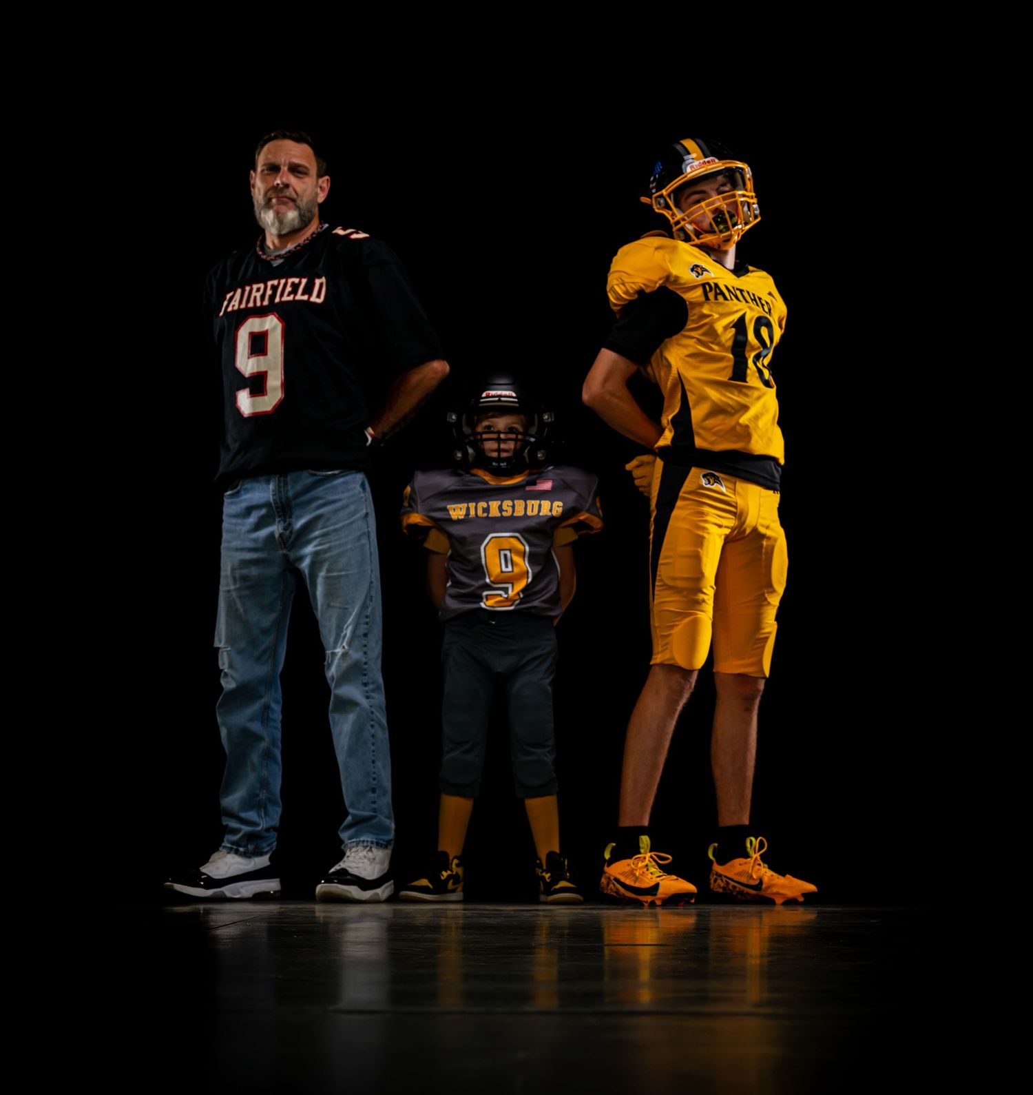 Man in Fairfield jersey poses with two youth football players in team uniforms.