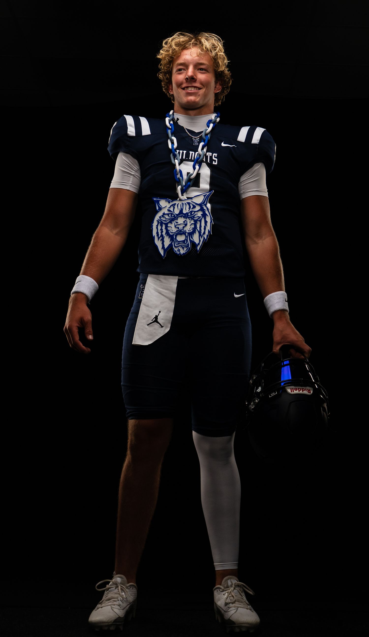 Football player in navy and white uniform stands in athletic stance.
