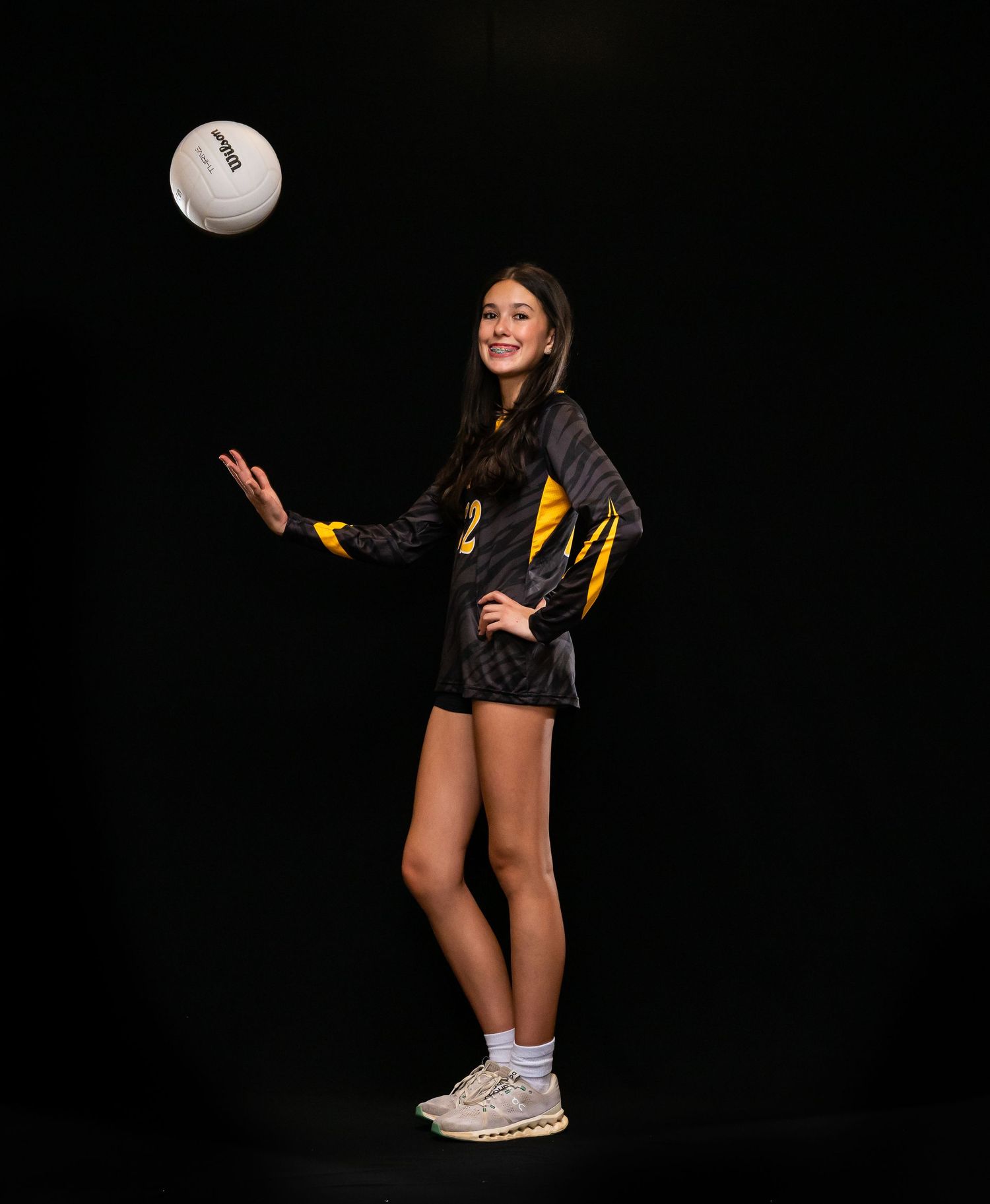 Volleyball player in black and yellow uniform sets up for a serve.
