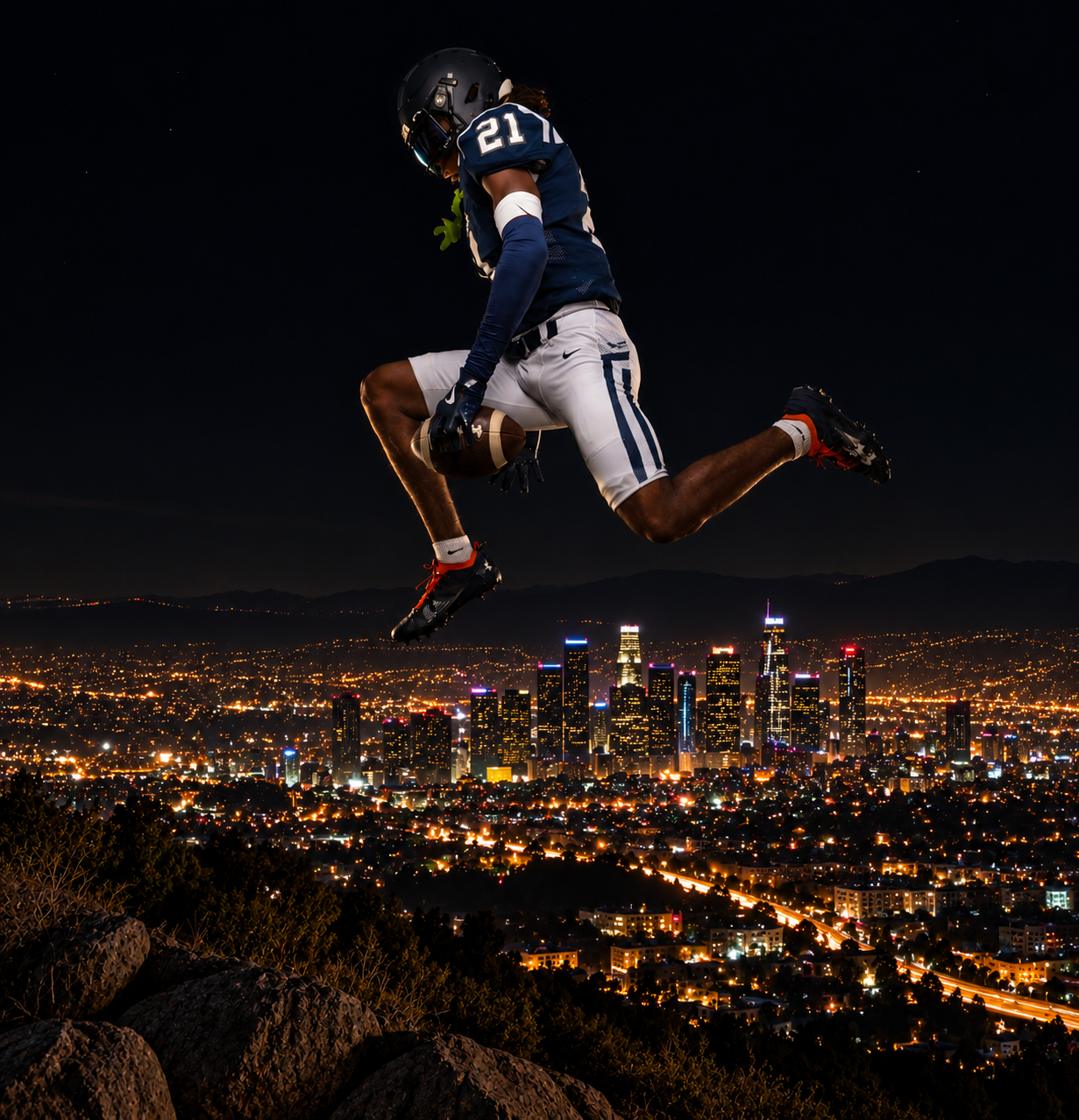 Football player #21 leaps dramatically above the glittering Los Angeles skyline at night in navy uniform.