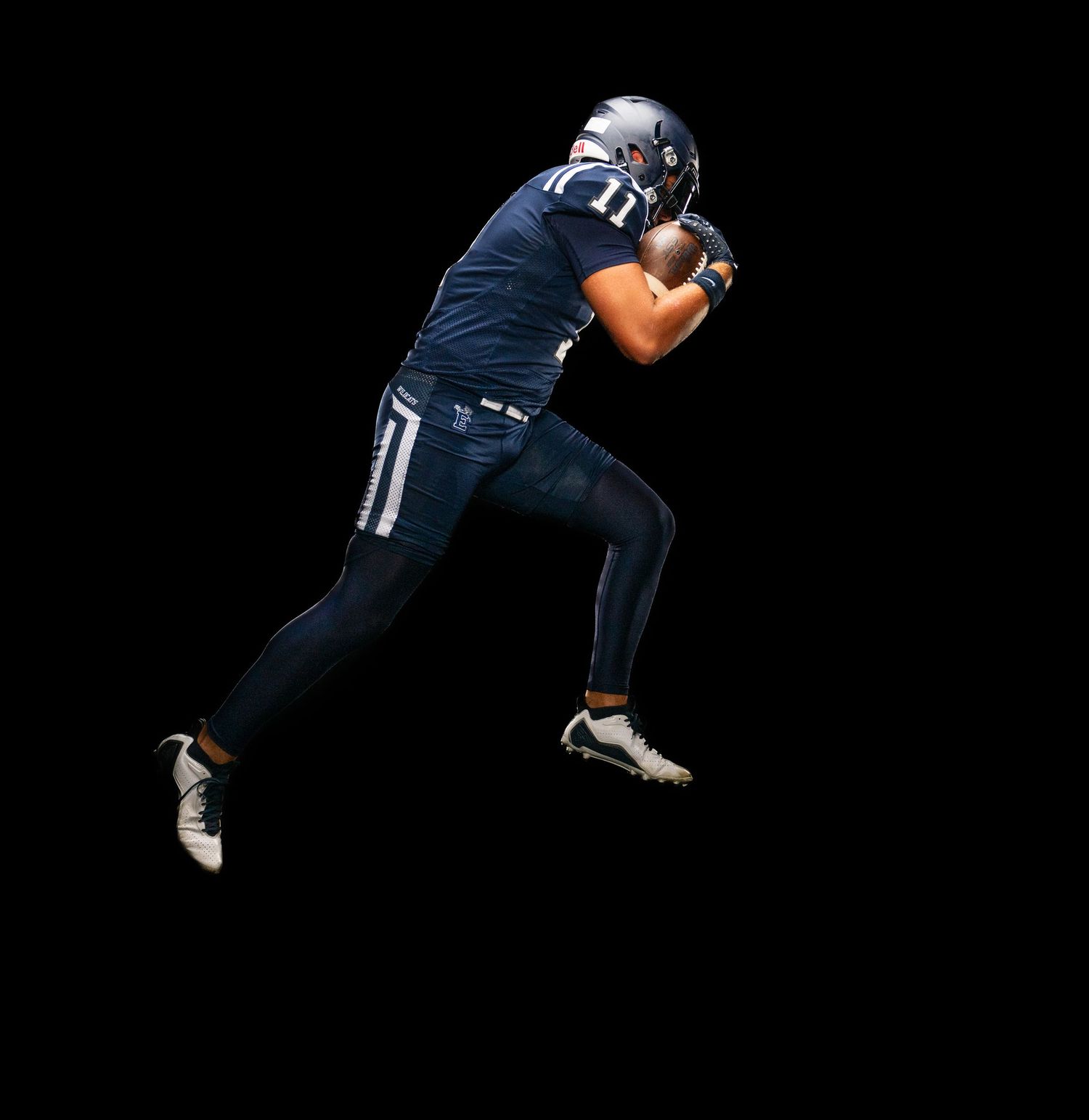 Football player in navy uniform charges forward in dynamic pose.