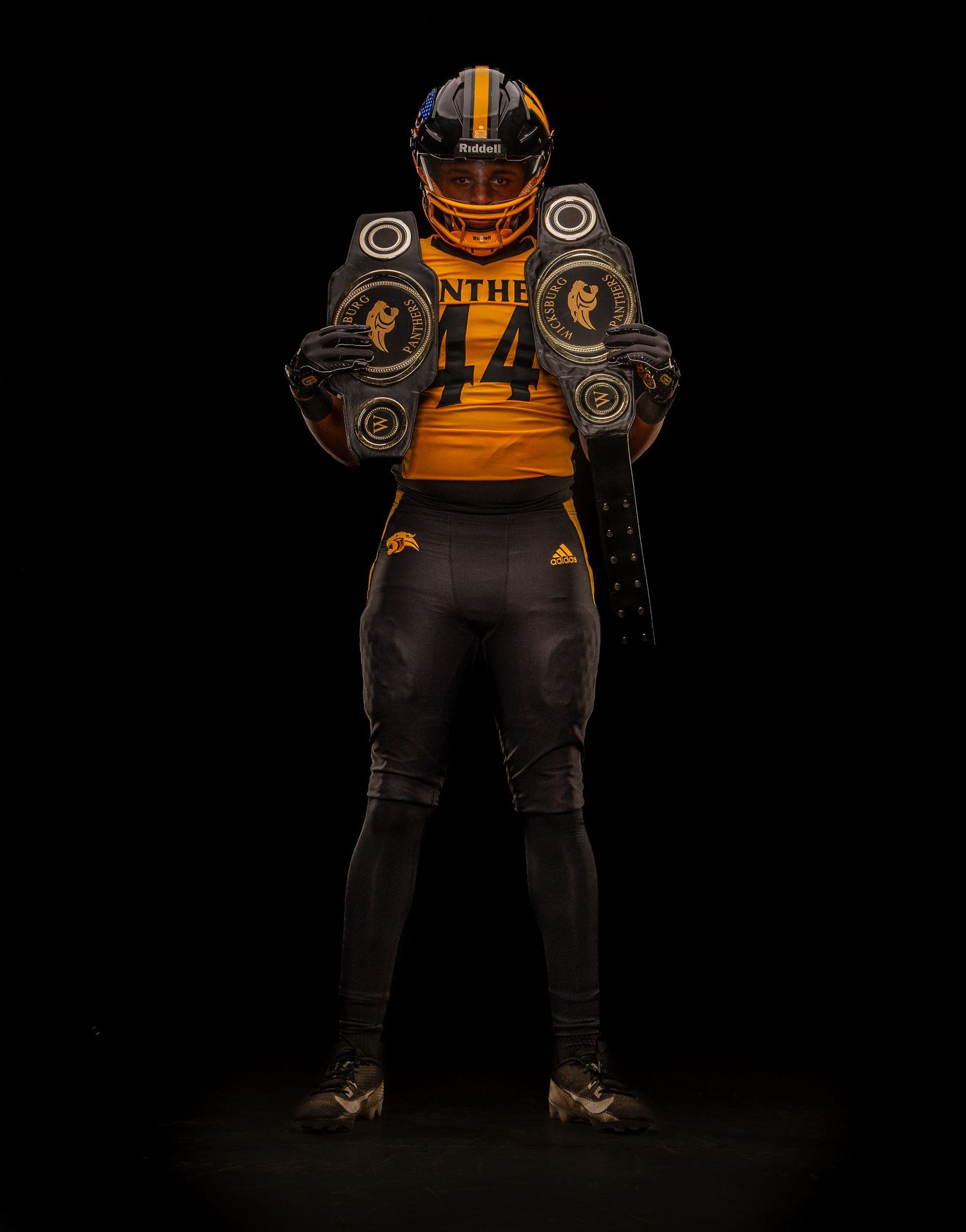 Football player wearing orange and black uniform photographed against dark backdrop.