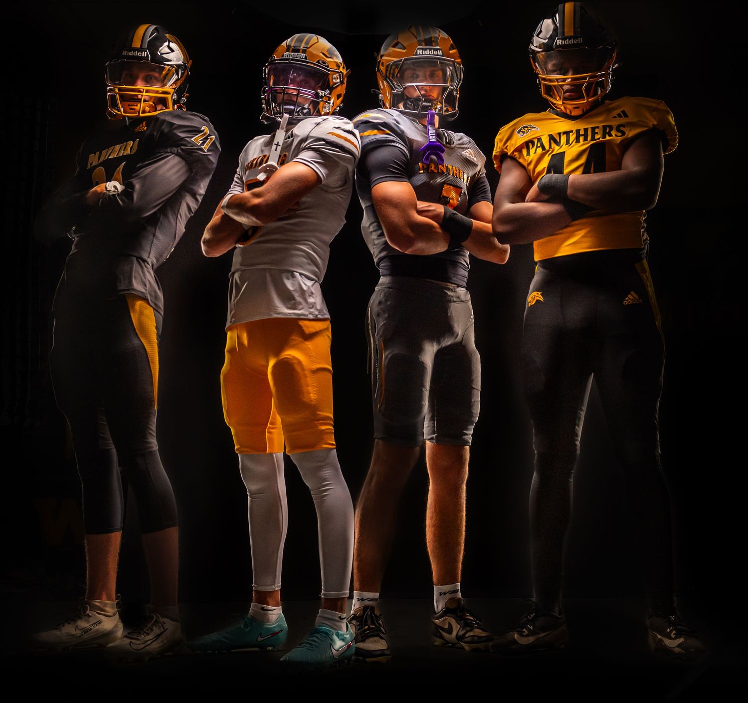 Dramatic dark sports photo showing football players lined up in orange and black uniforms with selective lighting.