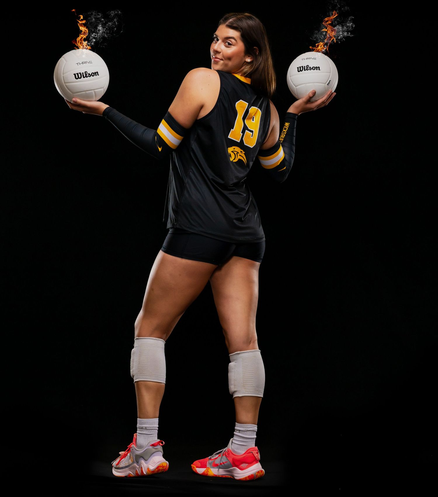 Athletes holding Wilson volleyballs showcase defensive stance with knee pads.