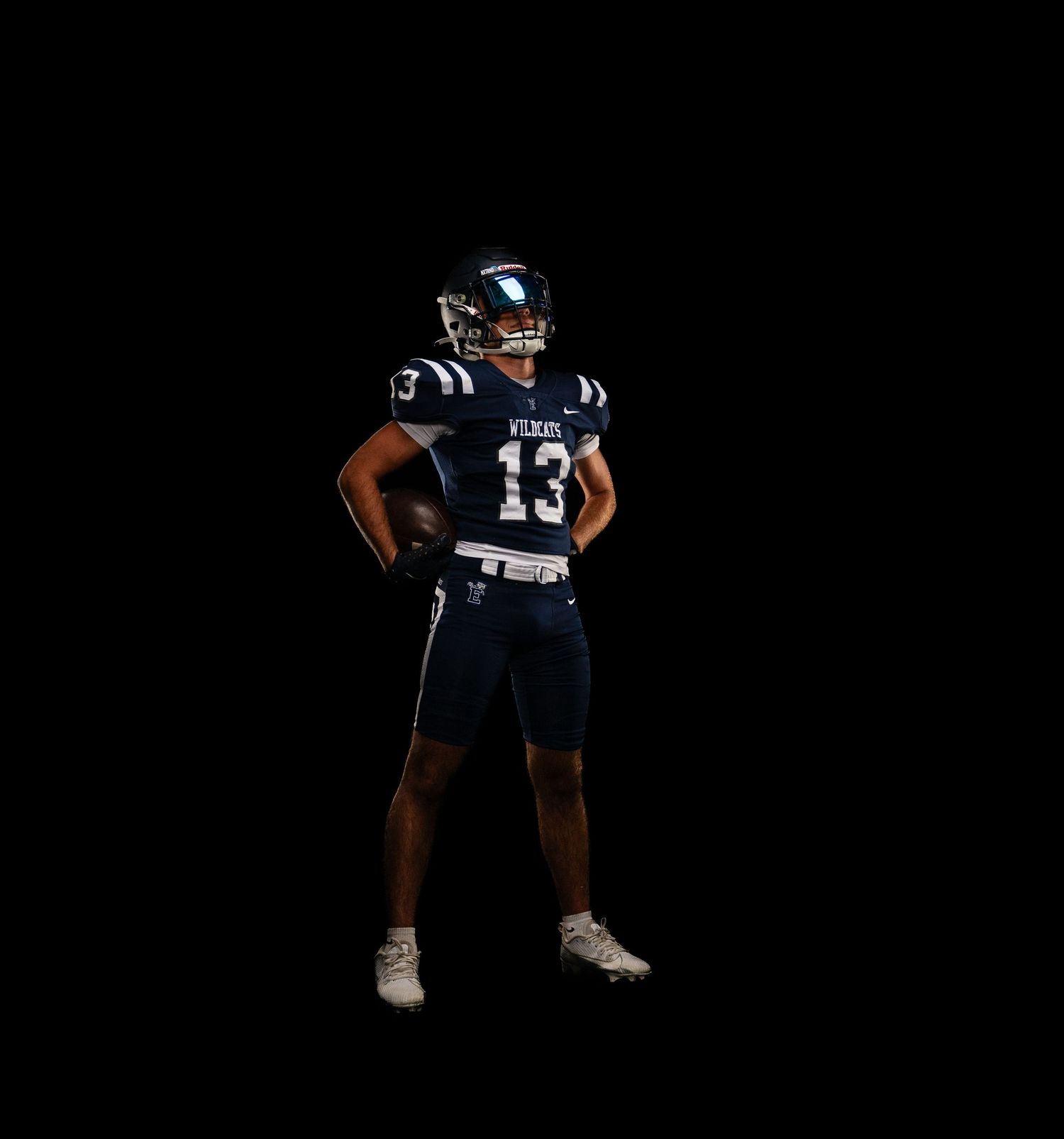 Football player wearing navy blue jersey number 13 posing confidently against a black background.