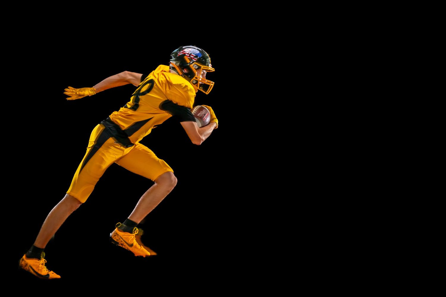 Football player in yellow uniform sprinting dynamically against black background.