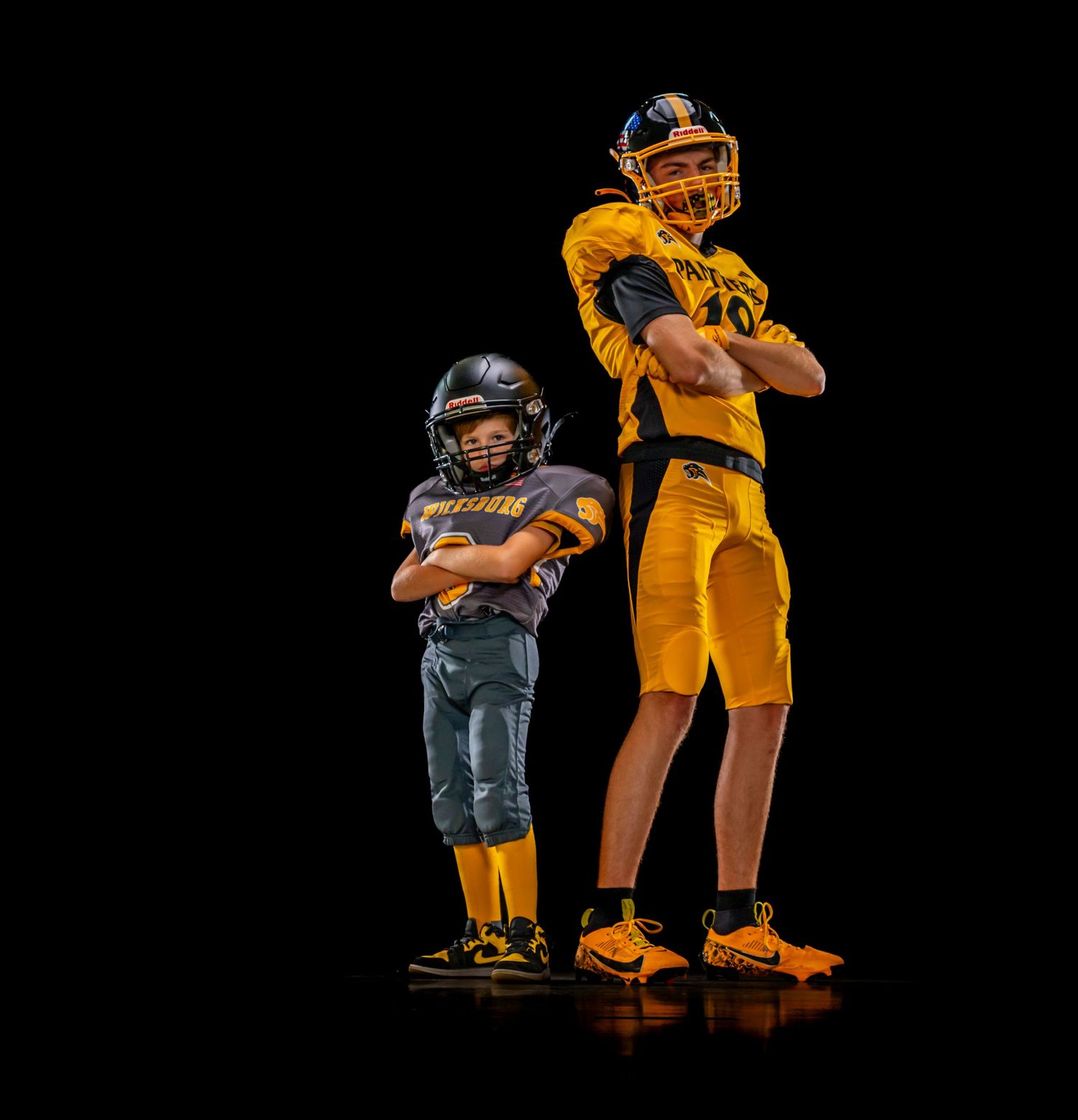 Baseball player in yellow uniform stands with catcher in black gear during game practice on field.