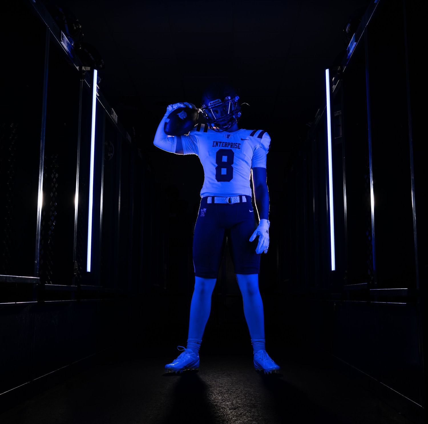 Football player in blue uniform number 8 posing dramatically in lit tunnel.