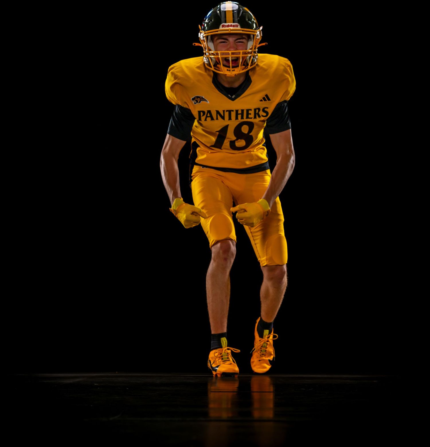 Football player in gold Panthers #18 jersey and helmet poses dramatically against black background.