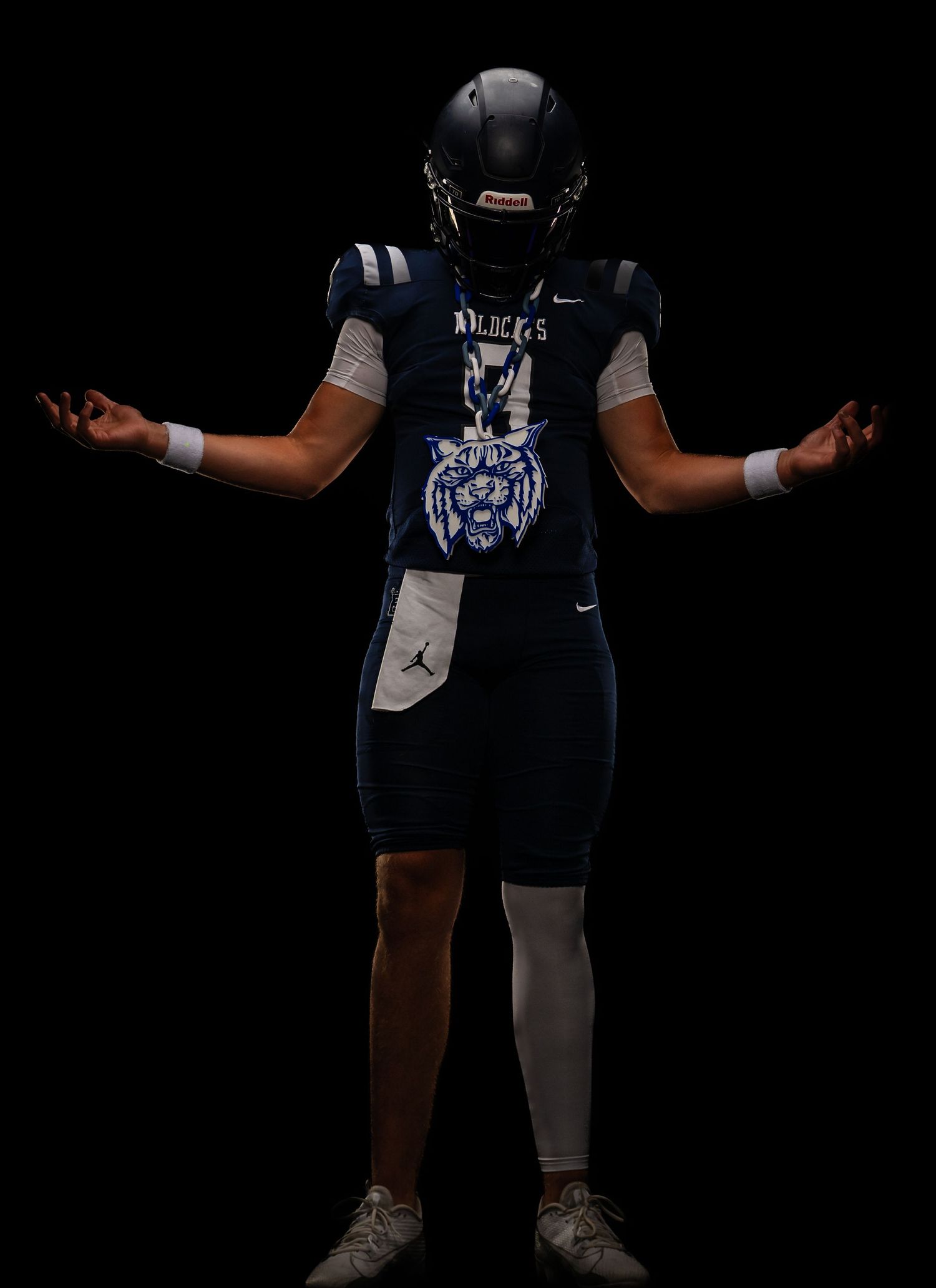 Football player in navy uniform with tiger logo and helmet poses with arms outstretched.