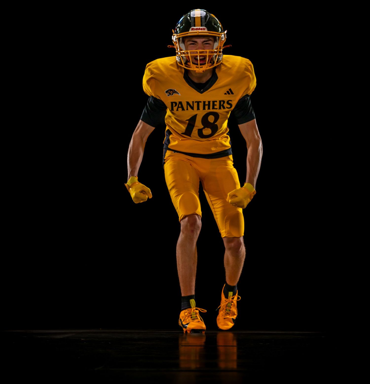 Football player in gold Panthers #18 uniform and helmet posed dramatically against black background.