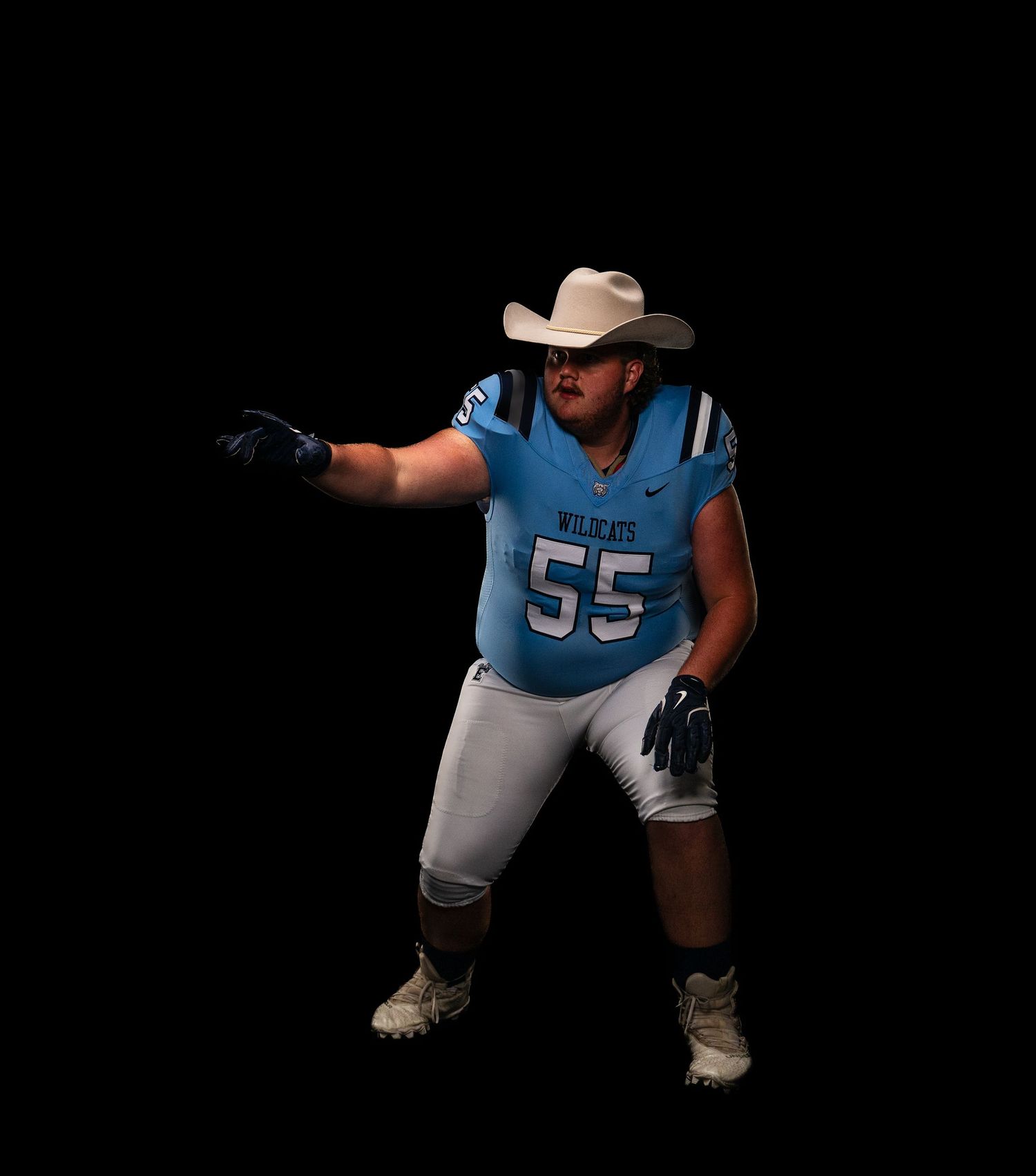 Football player in light blue uniform crouches in ready position.