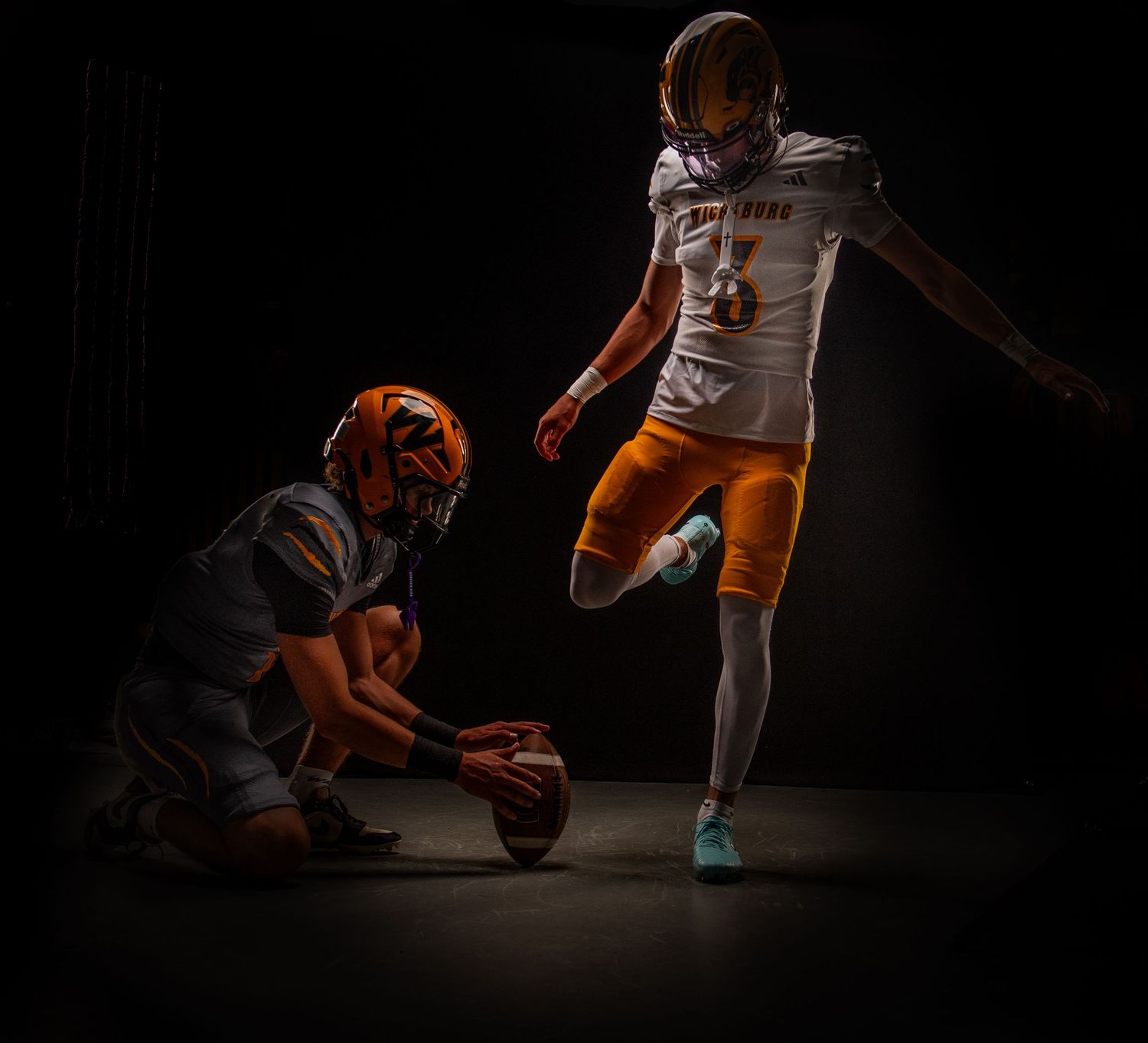 Dynamic low-angle action shot of athletes practicing football drills in dramatic lighting.