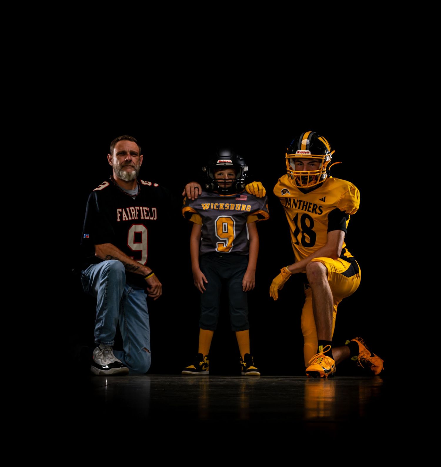 Three football players in Fairfield and Panthers uniforms pose dramatically on a dark stage.