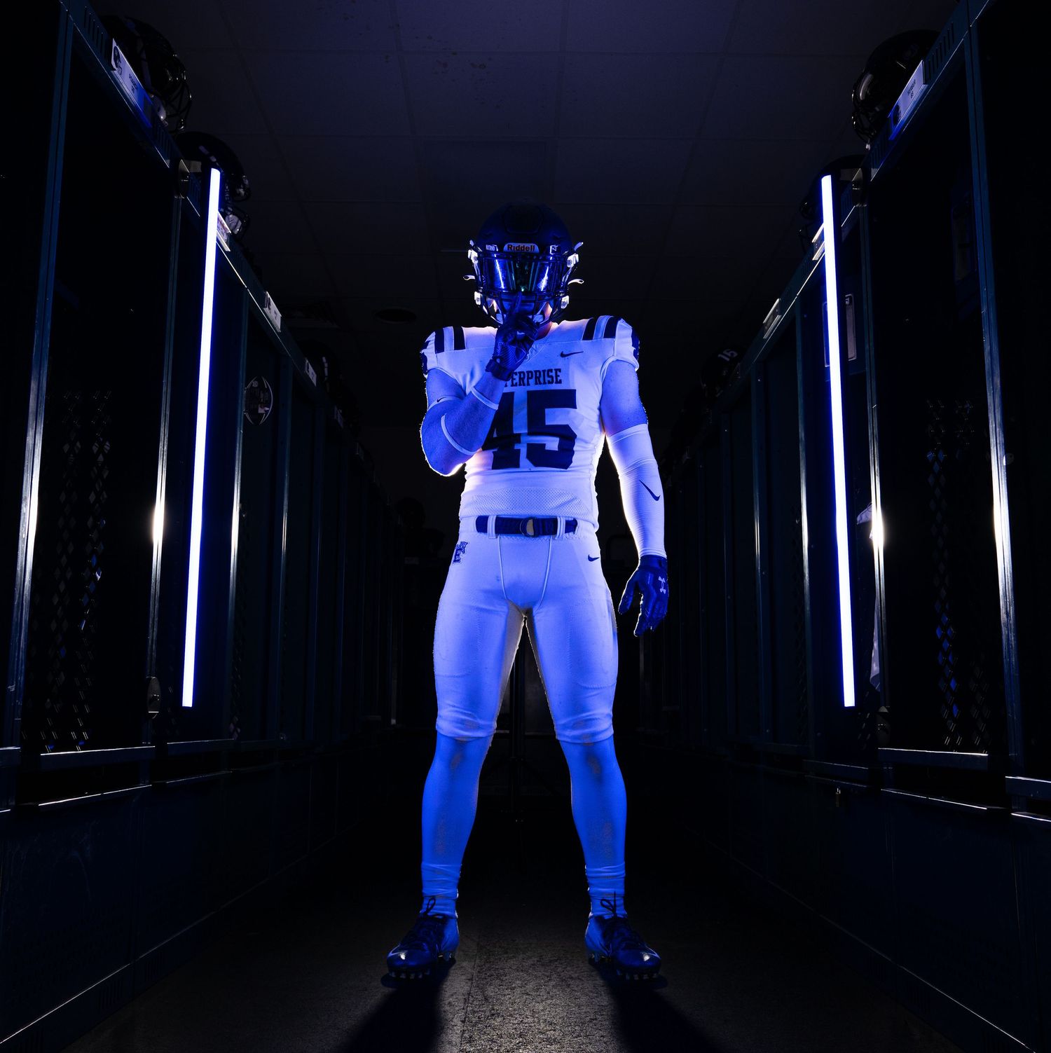 Football player in #45 blue and white uniform standing dramatically in illuminated tunnel entrance.